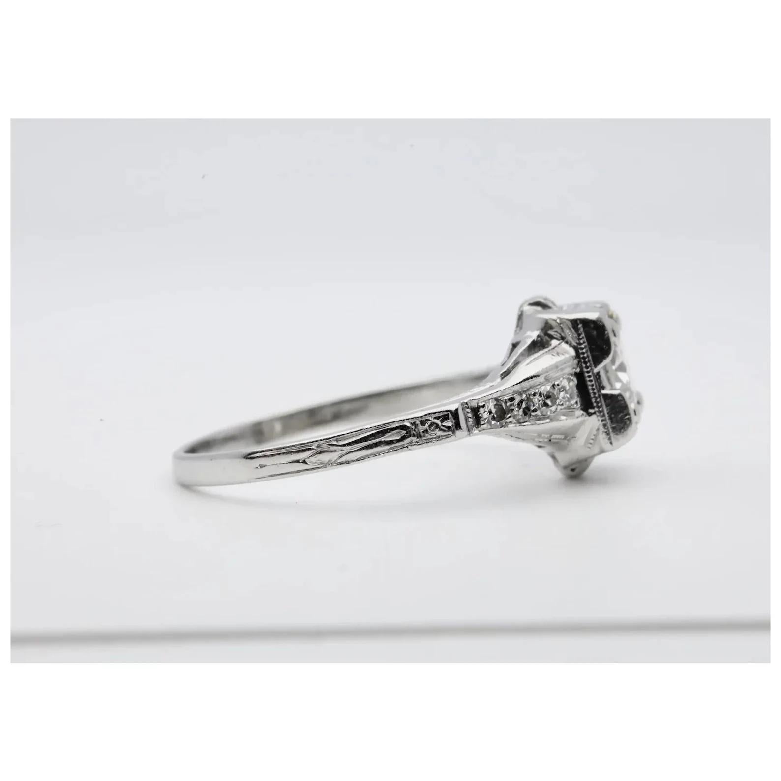 A handmade Art Deco period diamond engagement ring crafted in platinum. Centered by a 0.55 carat Old European cut center diamond of H color and VS2 clarity. Accenting this ring are an additional eight pave set diamonds weighing a combined 0.08