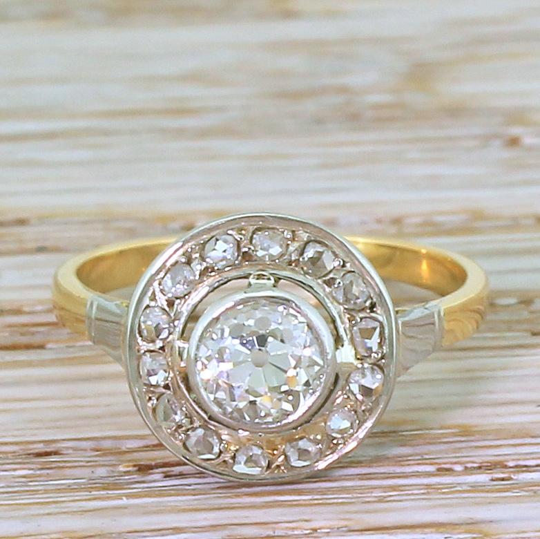 A desperately pretty vintage diamond cluster ring. The old cut diamond in the centre – graded by HRD as K colour, VVS2 clarity – is set within a platinum bezel which “floats” within halo of fourteen rose cut diamonds. The unfussy split gallery leads