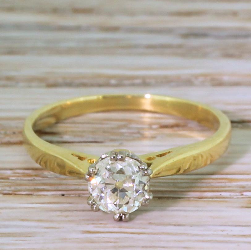 A timeless vintage diamond solitaire ring. The old mine cut in the centre displays a soft and subtle champagne hue with plenty of life and fire. The stone is secured in a fine, white gold collet with six double claws and hooped detailing in the
