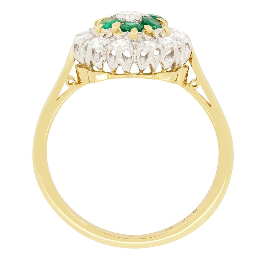 Une merveilleuse collection de diamants et d'émeraudes est exposée dans cette jolie bague à grappes des années 1930. Au centre de la pièce, un diamant de 0,10 carat est serti dans une tête en platine. Le diamant a été estimé de couleur F et de