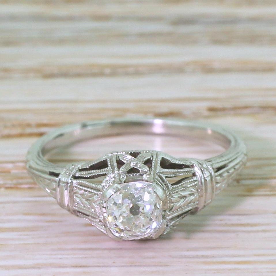 A fantastically detailed and beautiful Art Deco diamond solitaire ring. The old mine cut diamond which sits proudly in the centre is bright, white and full of internal fire. The highly intricate shank features vented shoulders with fine engraving