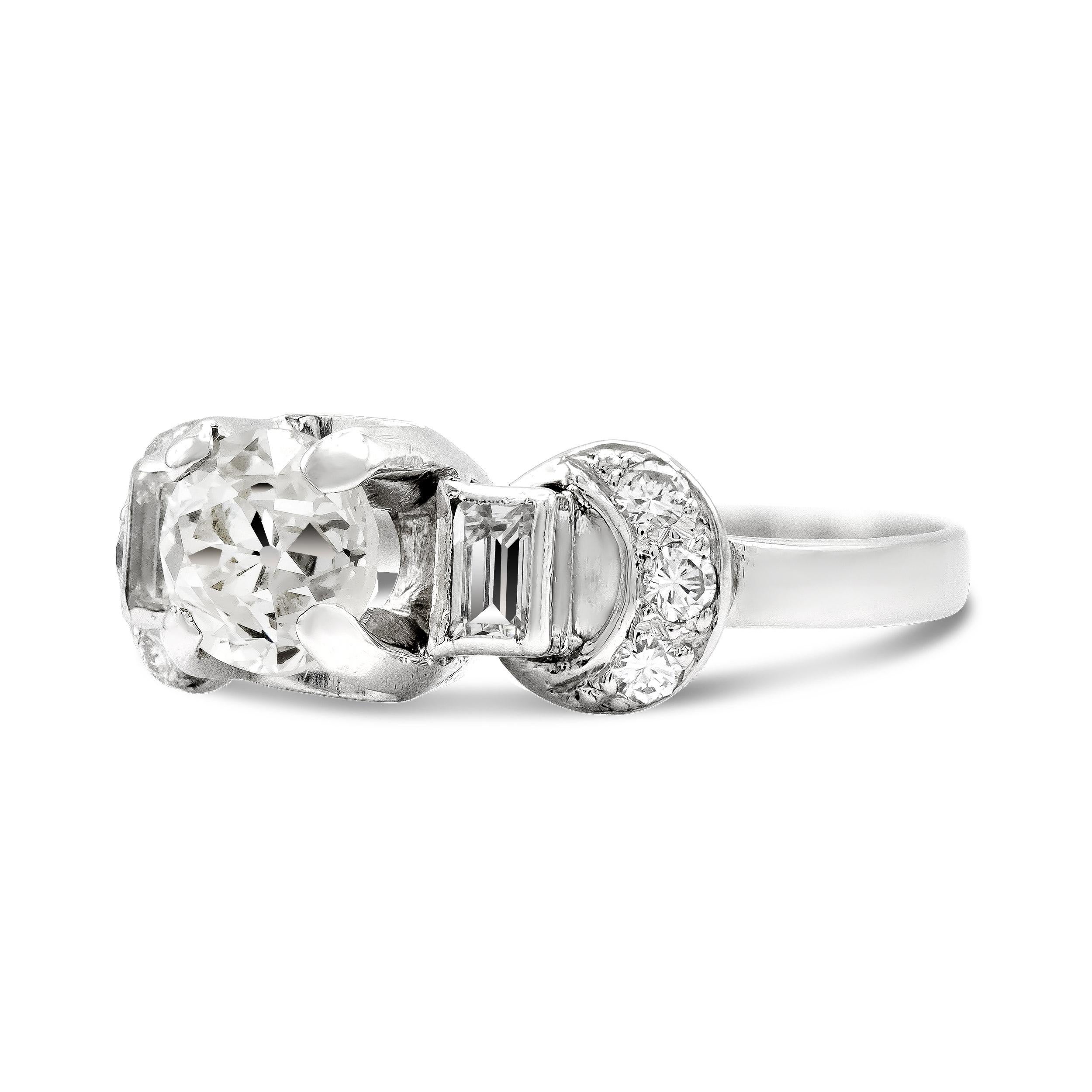 This one-of-a-kind engagement ring is sure to please any lover of deco design. Her tiered shoulders, adorned with straight baguettes and old European cut diamonds are an incredible example of the beauty of deco. The center diamond looks like the