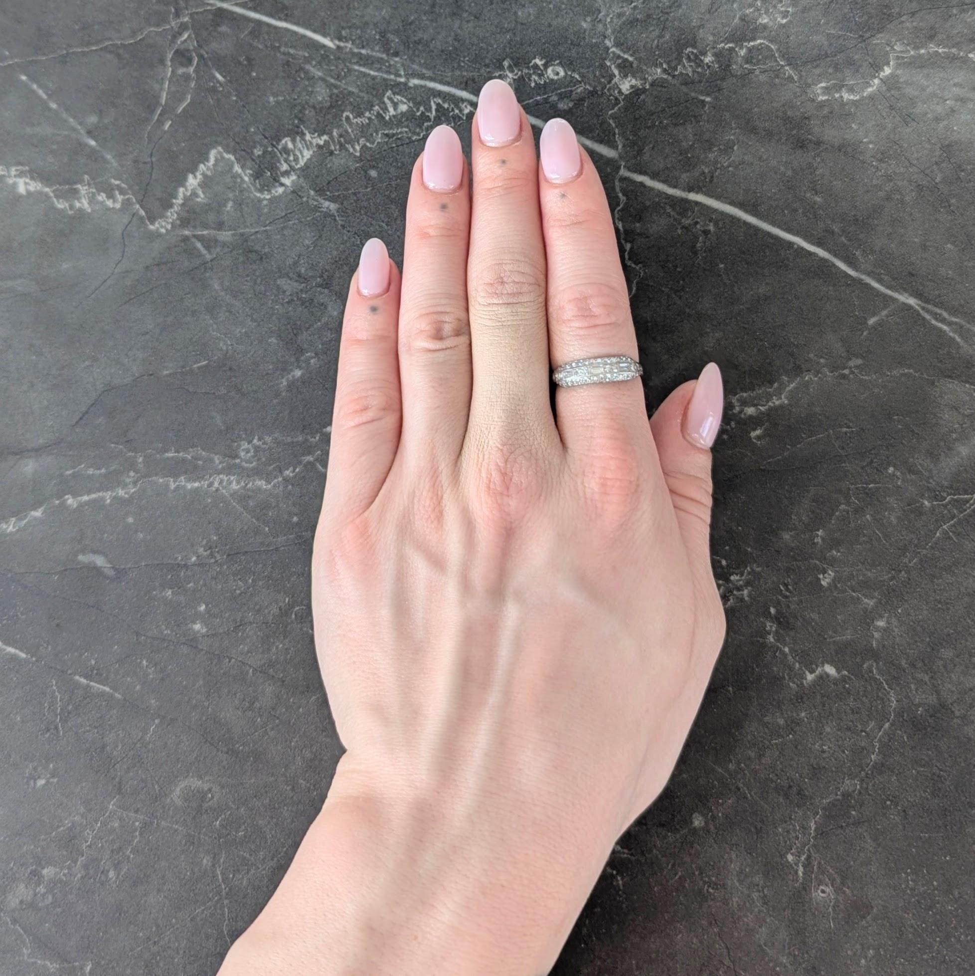 Centering three parallel rows of single and baguette cut diamonds channel set to front
Weighing approximately 0.72 carats total - G/H color with VS2 clarity
Flanked by grooved column motif shoulders
Accented by milgrain detail
Tested as