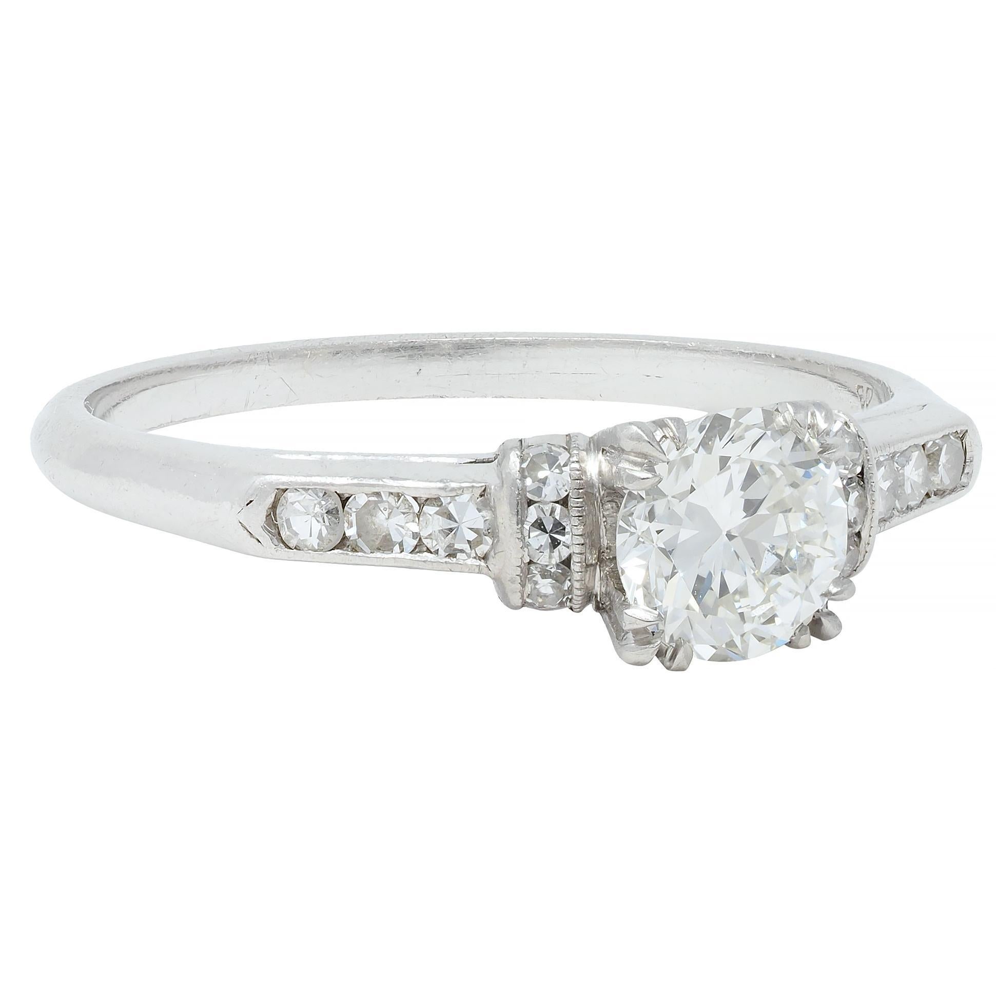 Centering a transitional cut diamond weighing approximately 0.60 carat total - G color with VS2 clarity
Set with tri-split prongs in a square form basket - pierced with a 'W' motif profile 
Flanked by rounded arches and cathedral shoulders set with