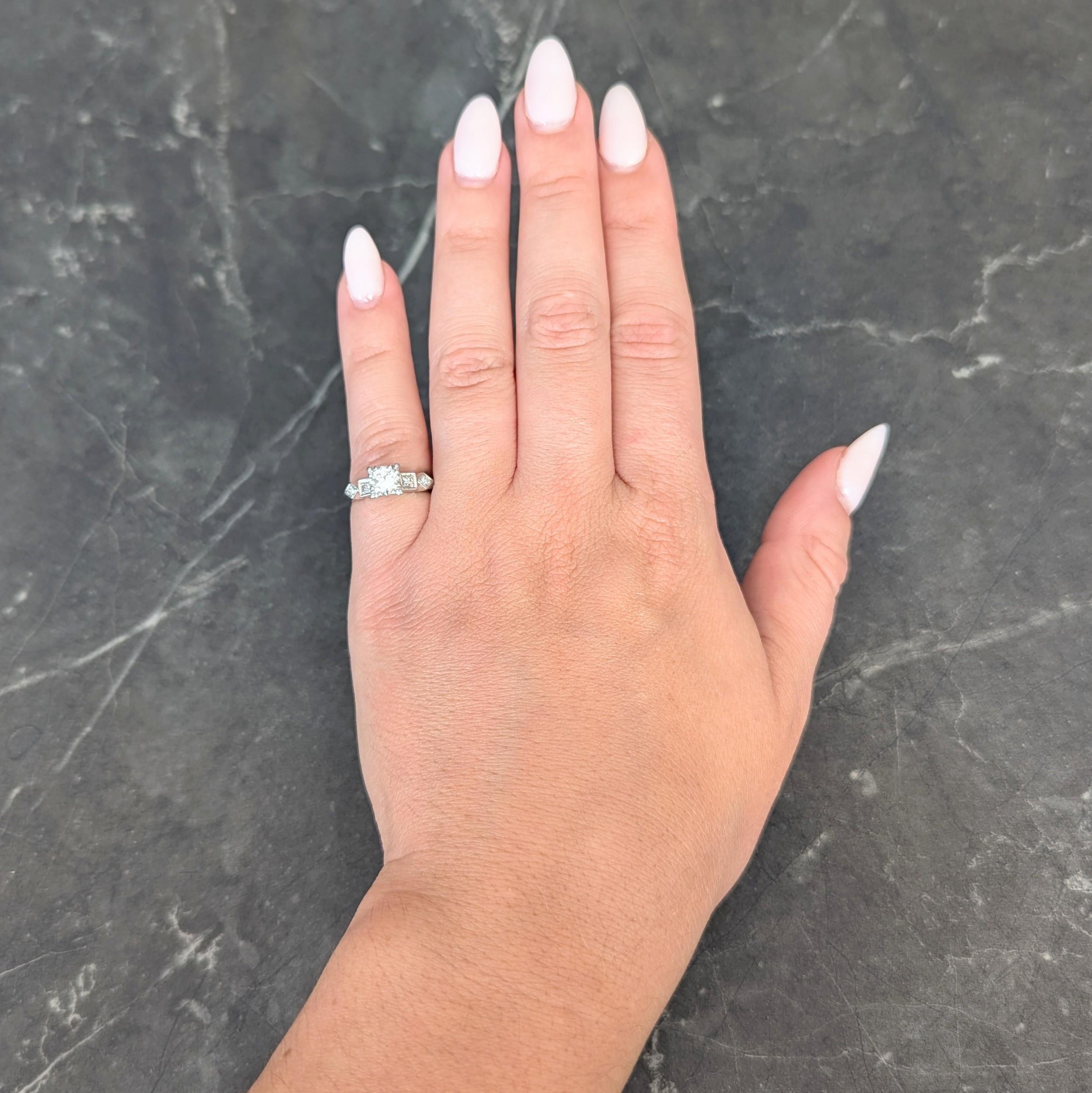 Centering a transitional cut diamond weighing approximately 0.60 carat -I color with VS clarity
Set by tri-bead prongs in a stylized square form head flanked by geometric form shoulders
Bead set with single cut diamonds weighing in total