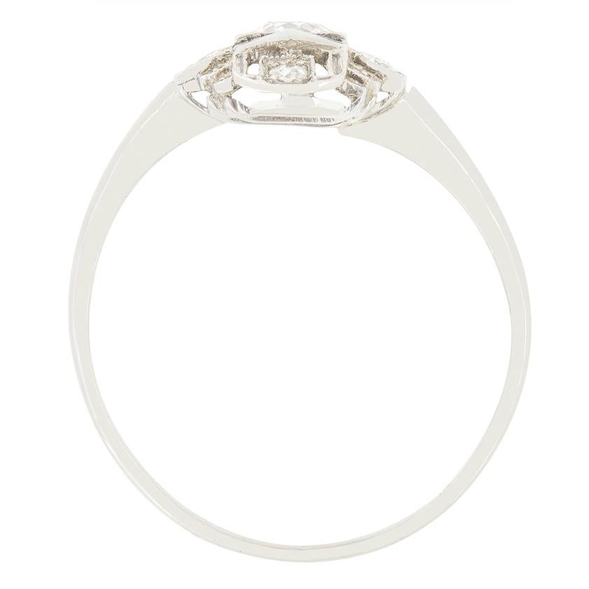 Dieser einzigartig gestaltete Ring wurde im Stil des Art déco gefertigt. Im Zentrum des aus 18 Karat Weißgold gefertigten Schmuckstücks stehen zwei 0,25 Karat schwere Diamanten im Altschliff. Um diese Steine herum sind in komplizierten