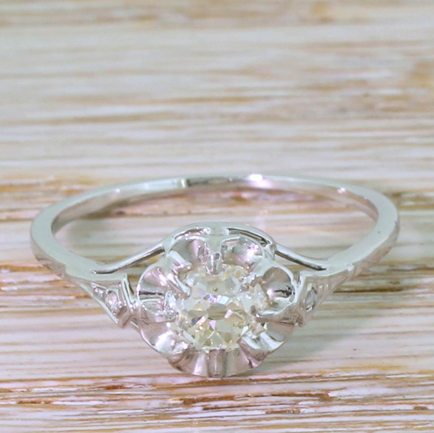 A vintage diamond engagement ring of real class. The 0.82 carat old mine cut diamond in the centre is secured in an eight-claw open collet above a scalloped back plate, allowing maximum light into this bright, lively and exceptionally internally