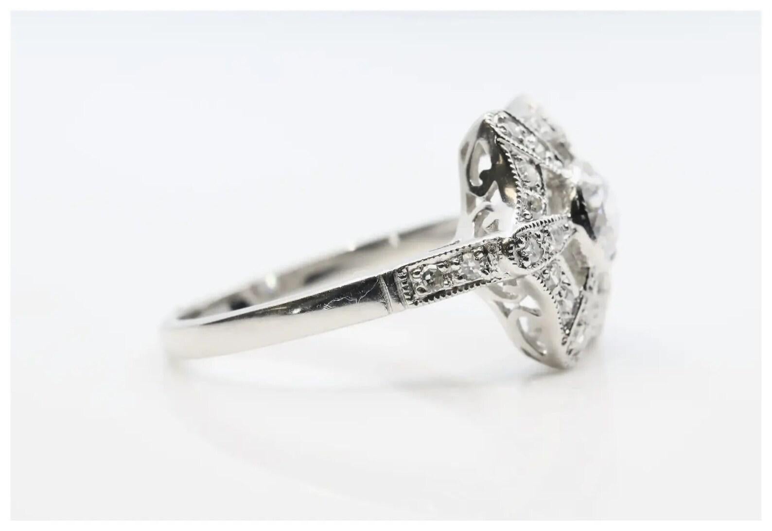 An Art Deco style diamond engagement ring in platinum.

Centered by a bezel set old European cut diamond of 0.55 carats having G color and VS2 clarity.

Accented by diamond set rays, and a halo of pave set diamonds with 28 accenting diamonds of
