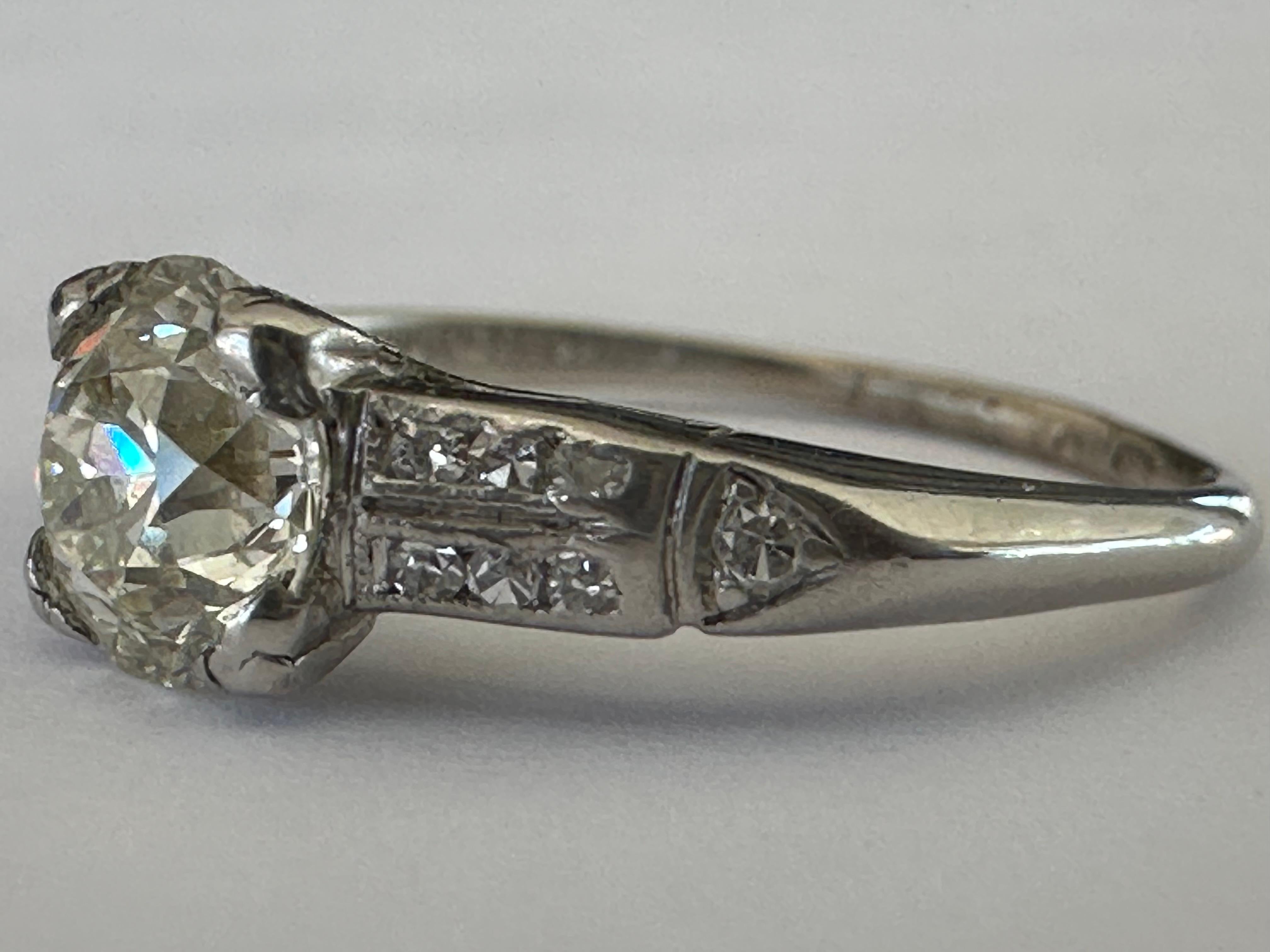 An Old European cut diamond center stone measuring approximately 0.88 carat, J color VS clarity, shines brilliantly between shoulders studded with twelve single cut diamonds totaling approximately 0.14 carat. Set in platinum. Circa 1920s. 
