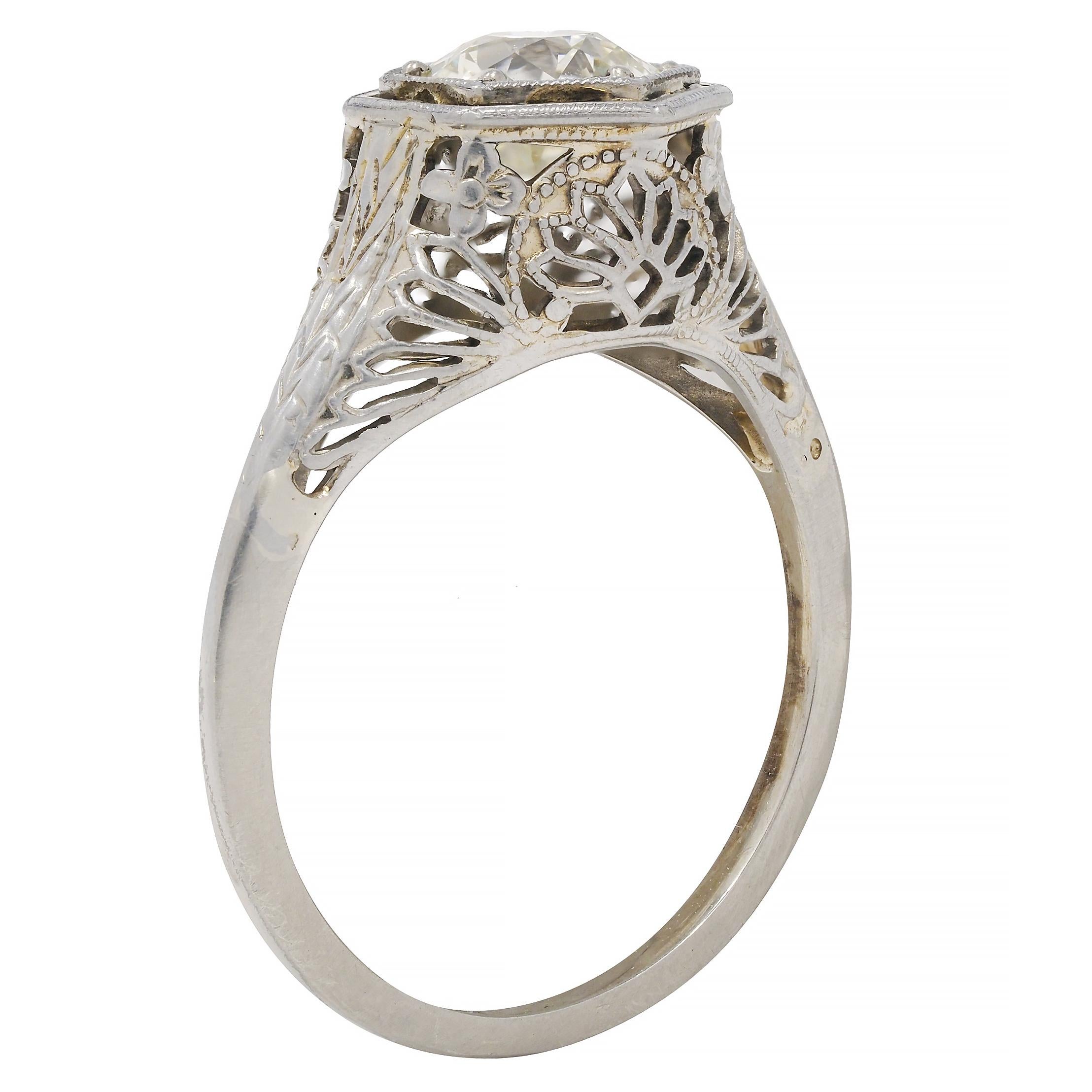 Centering an old European cut diamond weighing approximately 0.90 carats - P color with SI2 clarity
Bead set in a hexagonal form head with miligrain surround 
With engraved orange blossom motif throughout 
Flanked by engraved wheat motif shoulders