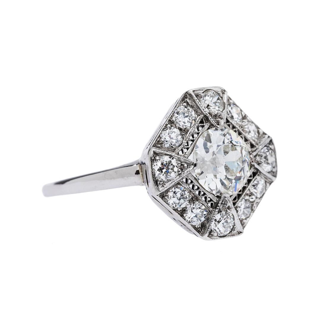 This is a striking and authentic Art Deco (circa 1925) platinum ring with a later added 14k white gold shank. The ring centers a 0.94ct EGL certified Old European Cut diamond graded H color and VS2 clarity, prong set and surrounded by hand pierced