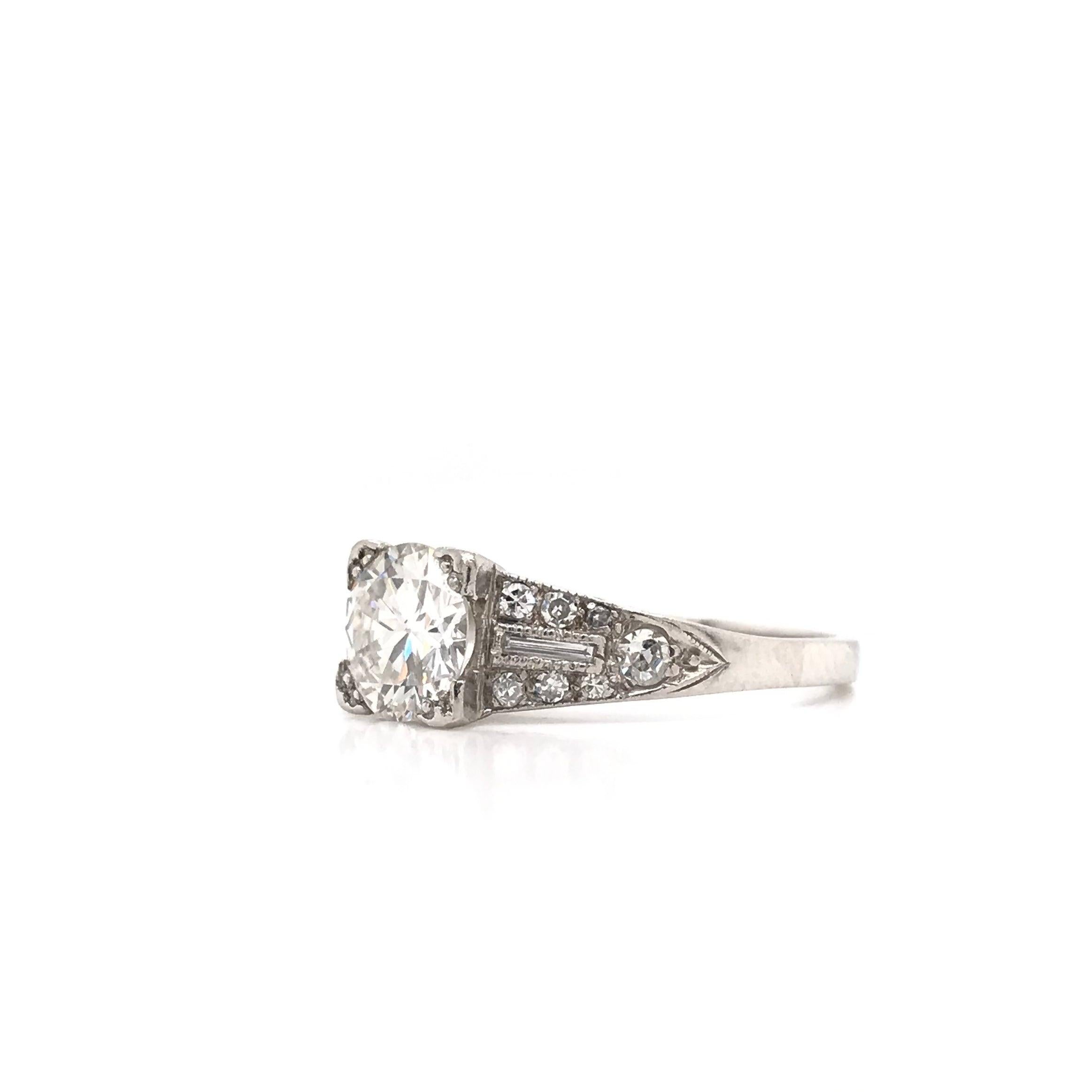 This stunning antique piece was handcrafted sometime during the Art Deco design period ( 1920-1940 ). The platinum setting features a beautiful center diamond measuring approximately 0.94 carats. The center diamond grades approximately H in color,