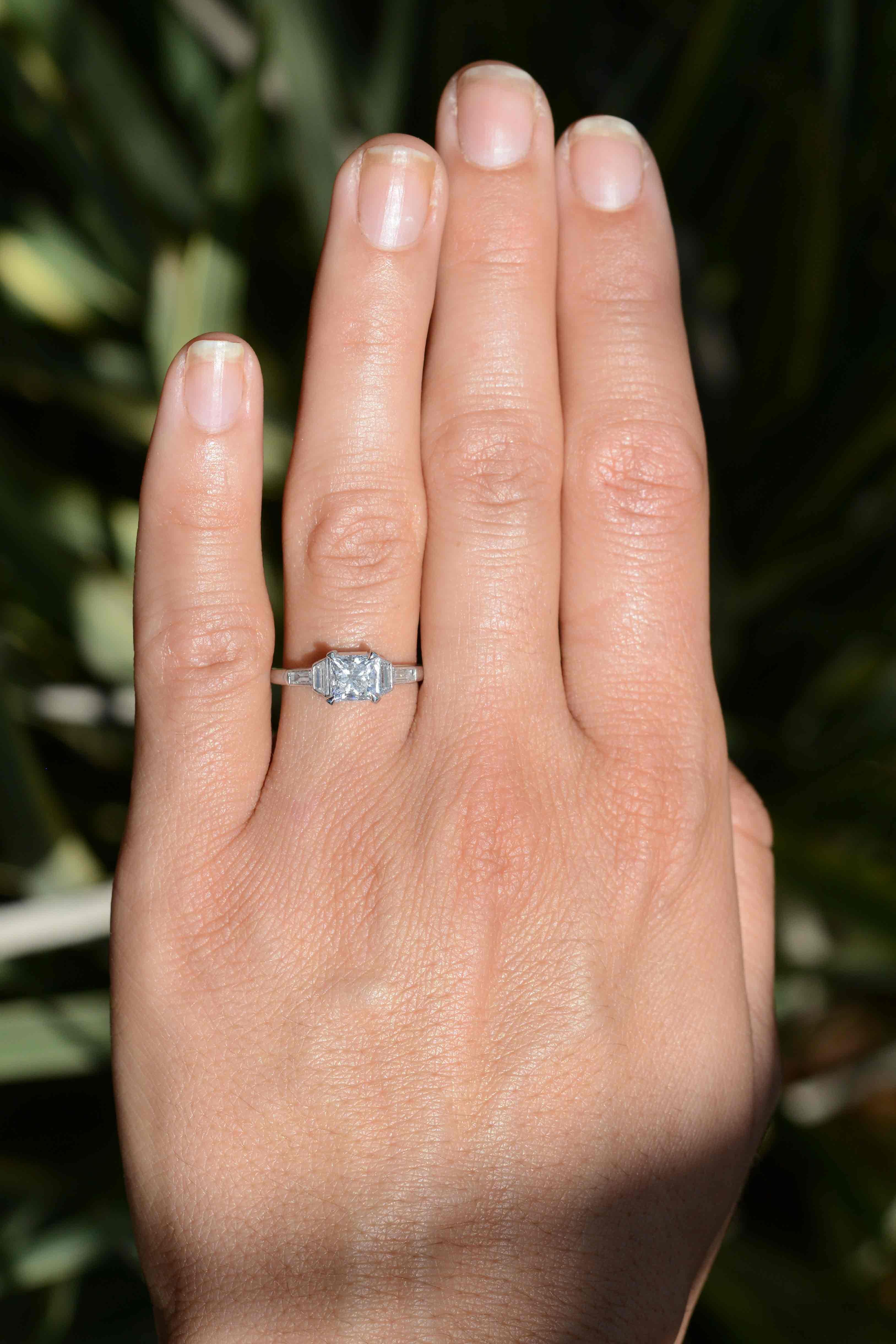 The La Jolla Art Deco 1 carat princess cut diamond engagement ring is an elegant bridal heirloom. The low setting is centered by an EGL certified sizzling F color square diamond, and the platinum solitaire smartly complimented by baguette and