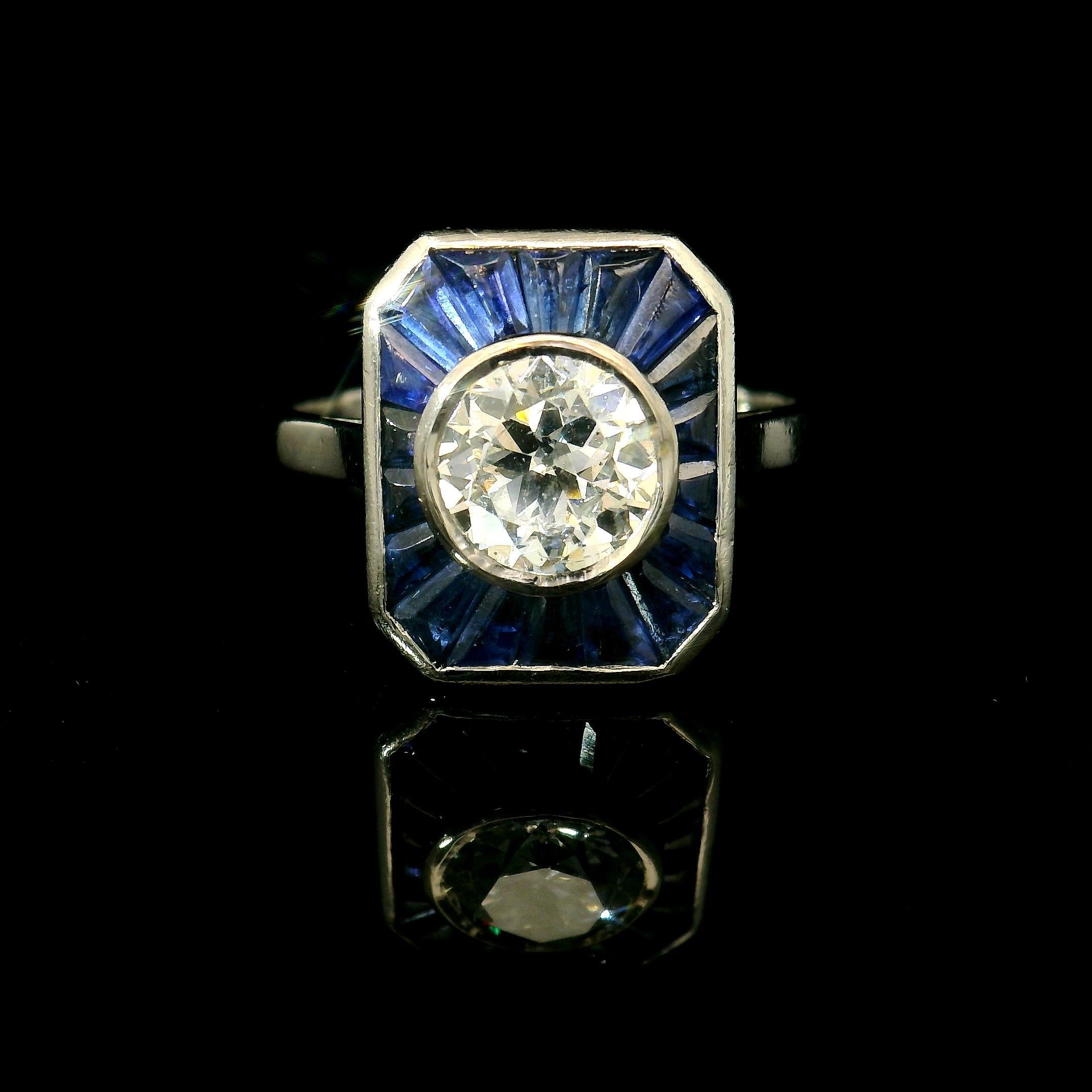 Bague en or blanc 18Kt.

Diamant central de +/- 1,00 Ct (H-Si) entouré de 18 saphirs calibrés. C'est une bague très bien faite. Vous pouvez voir au dos de la bague qu'elle est vraiment bien finie. 

Il s'agit d'une bague de haute qualité. 

Poids :
