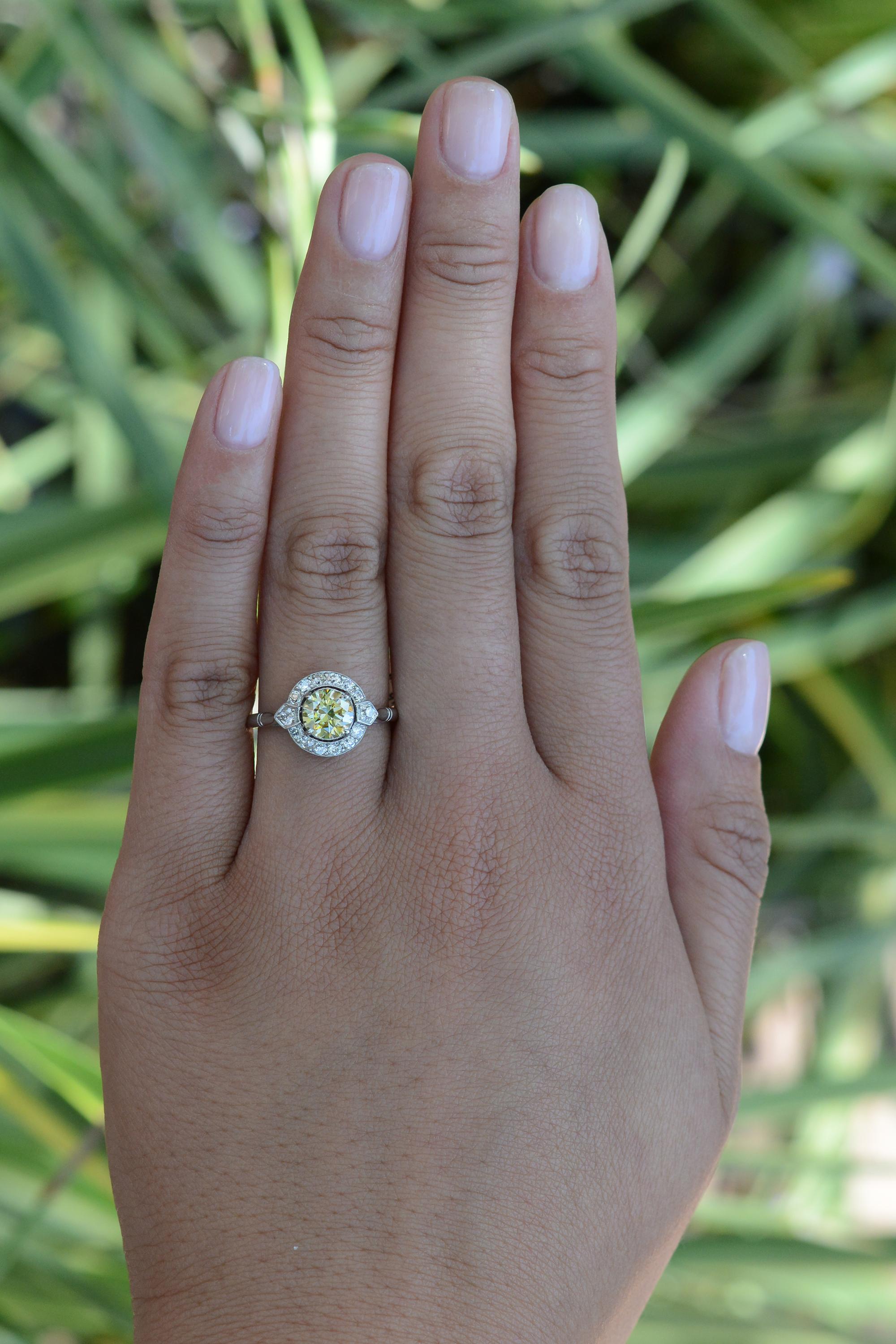 Celebrate your special moment with this timeless, vintage diamond engagement ring from the 1920s. With its prominent and glowing old European cut round yellow diamond, this authentic Art Deco era masterpiece offers unique glamour and undeniable