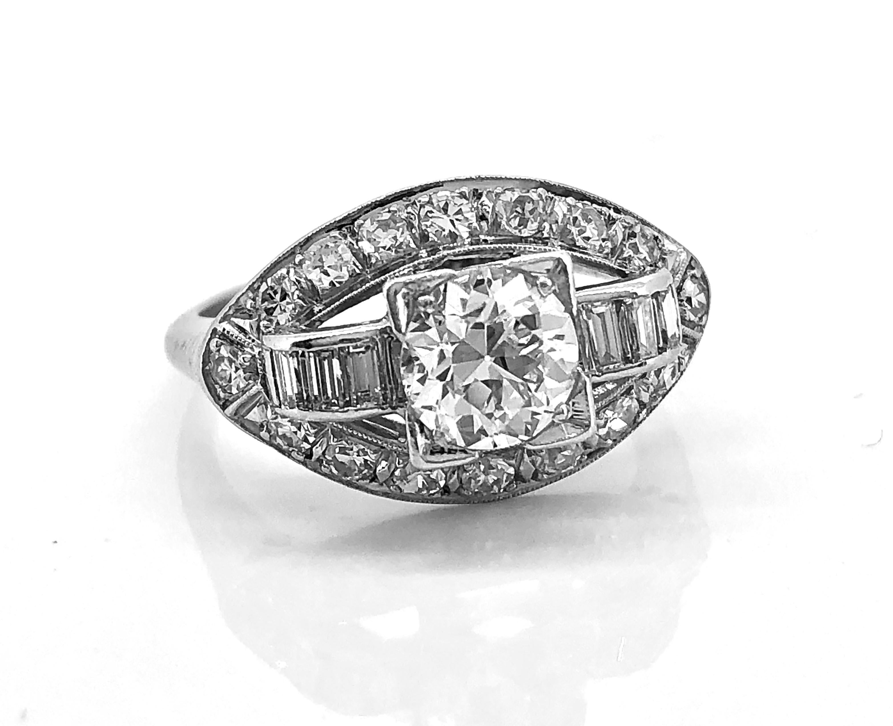 A gorgeous platinum antique engagement ring featuring a 1.00ct. apx. European cut center diamond with VVS2 clarity and J-K color. The diamond encrusted oval mounting is extraordinary featuring .50ct. apx. T.W. of single and baguette cut diamonds.