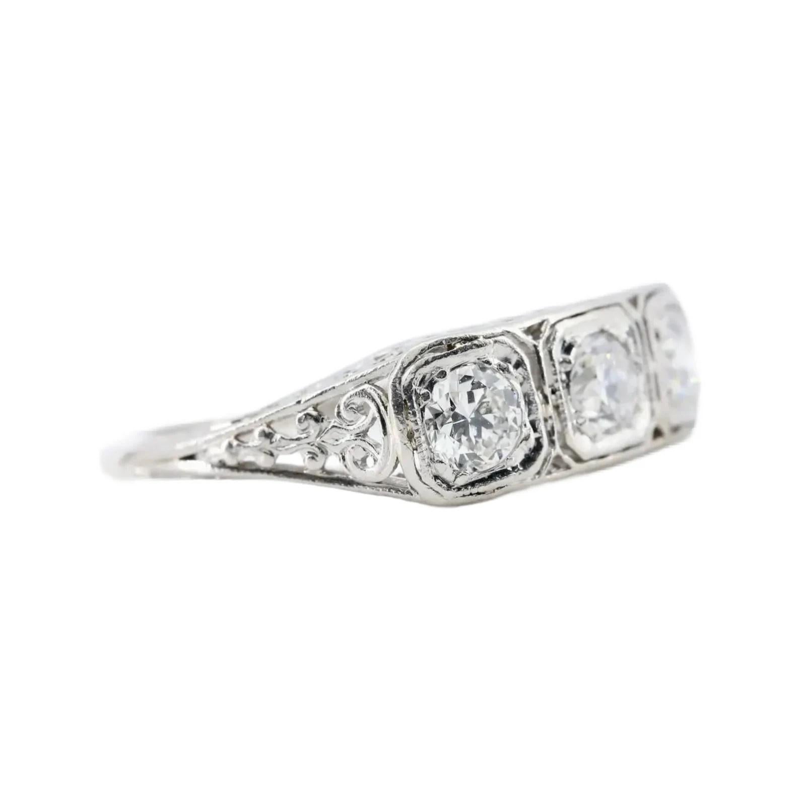 An Art Deco period three stone old European cut diamond ring crafted in platinum.

Centered by a trio of Old European Cut diamonds weighing 1.00 CTW with H color and VS2 clarity.

The hand pierced and engraved mounting adorned with flowers and