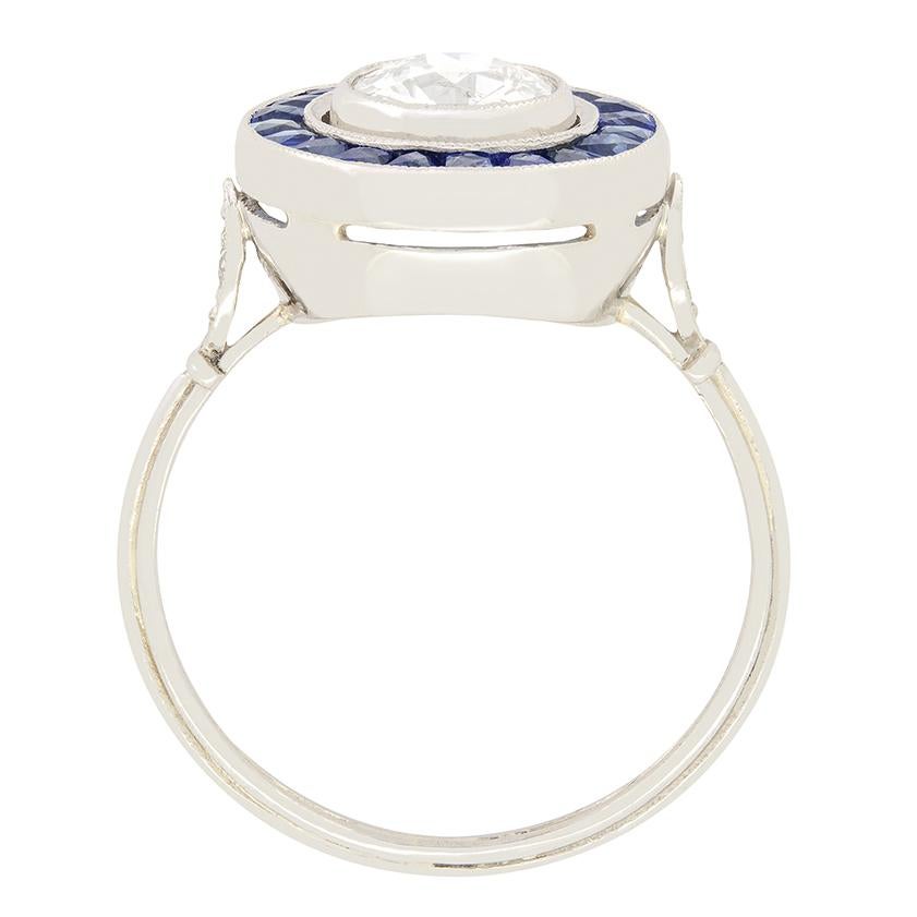 Featuring an impressive 1.00ct diamond at it’s centre this Art Deco era target ring is truly eye catching. The central diamond is an old cut stone with a  colour of H and a clarity of SI1. Enveloping the diamond, a halo of deep blue sapphires