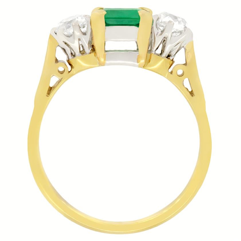 A beautiful 1.00 carat Emerald sits in between a pair of old cut diamonds in this twist on the classic trilogy ring. The emerald cut central stone is claw set into 18 carat yellow gold, with the diamonds set in platinum. The diamonds range in colour