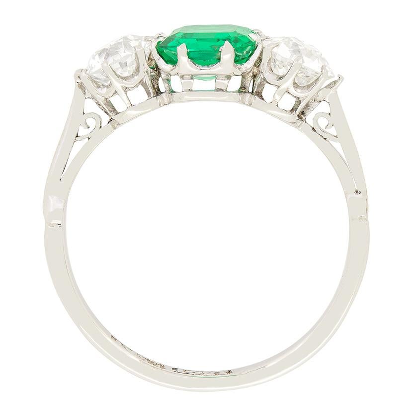 An exceptional Art deco era piece, this stunning trilogy ring features a Colombian emerald at its centre flanked by a pair of old cut diamonds. The 1.00 carat central emerald is a natural vivid green colour. The diamonds either side are both of high