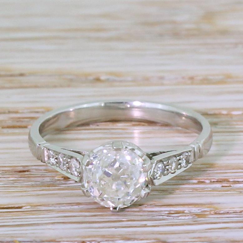 A fantastic old cut engagement ring. The centre diamond – graded by HRD as J colour, SI1 clarity  – is secured in a six claw collet with curved, sweeping detailing in the gallery. Wide, spear-shaped shoulders are set with six (three each side)