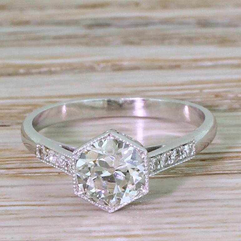 An absolutely gorgeous Art Deco engagement ring. The old European cut diamond in the centre – graded by HRD as J colour, SI1 clarity  – is secured in a finely milgrained hexagonal collet. Stylised detailing in the gallery leads to milgrained,