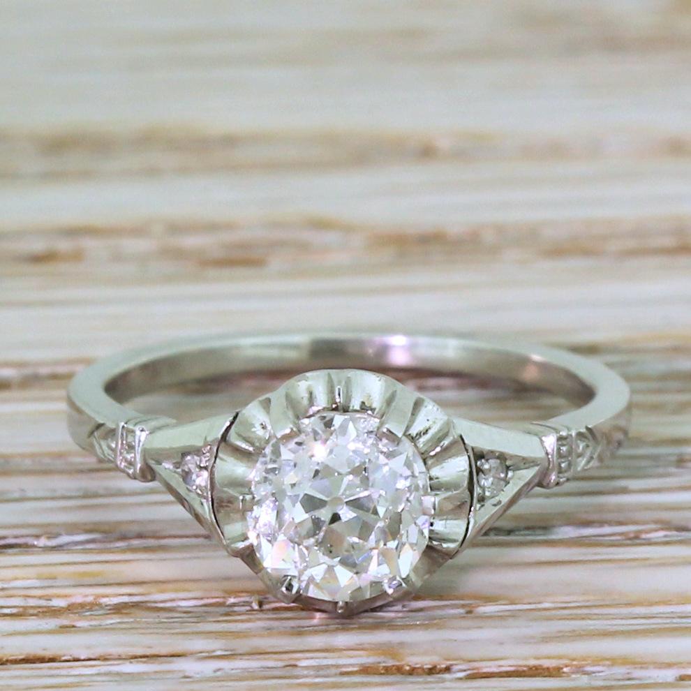 A staggeringly pretty antique engagement ring. The old cut diamond – graded by HRD as H colour, SI1 clarity – in the centre is white, bright and virtually glowing. The centre stone is secured an eight-claw collet above scalloped back-plate setting,