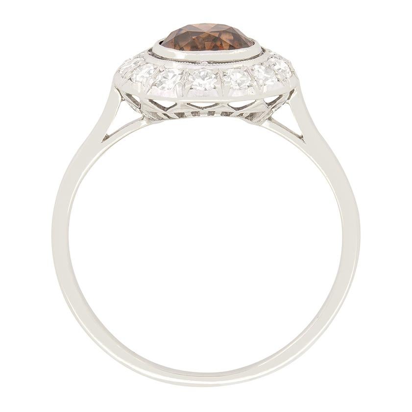 The Art Deco era’s opulent style is on display in this beautiful diamond halo ring. The unusual cognac coloured diamond is an old cut stone weighing 1.05 carat. With a colour of fancy brown and a clarity of SI1 the central diamond is truly