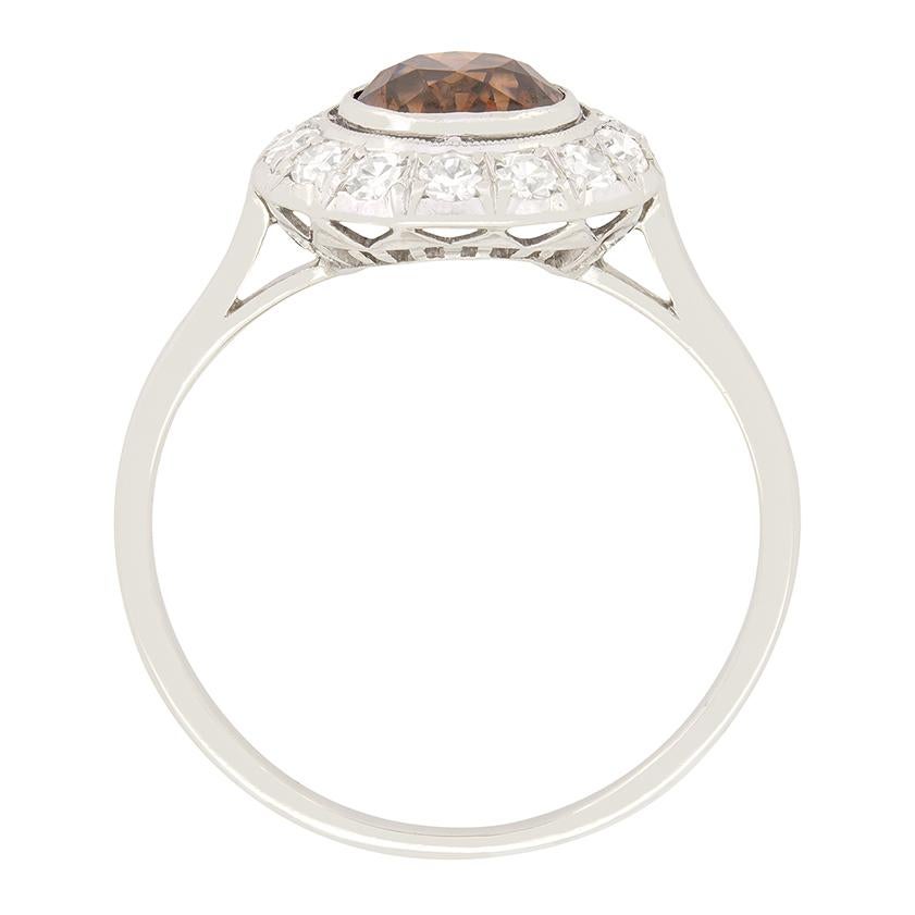 Der opulente Stil der Art-Déco-Ära zeigt sich in diesem wunderschönen Diamantring mit Halo. Der ungewöhnliche cognacfarbene Diamant ist ein Stein mit altem Schliff und einem Gewicht von 1,05 Karat. Mit einer Farbe von Fancy Brown und einer Reinheit