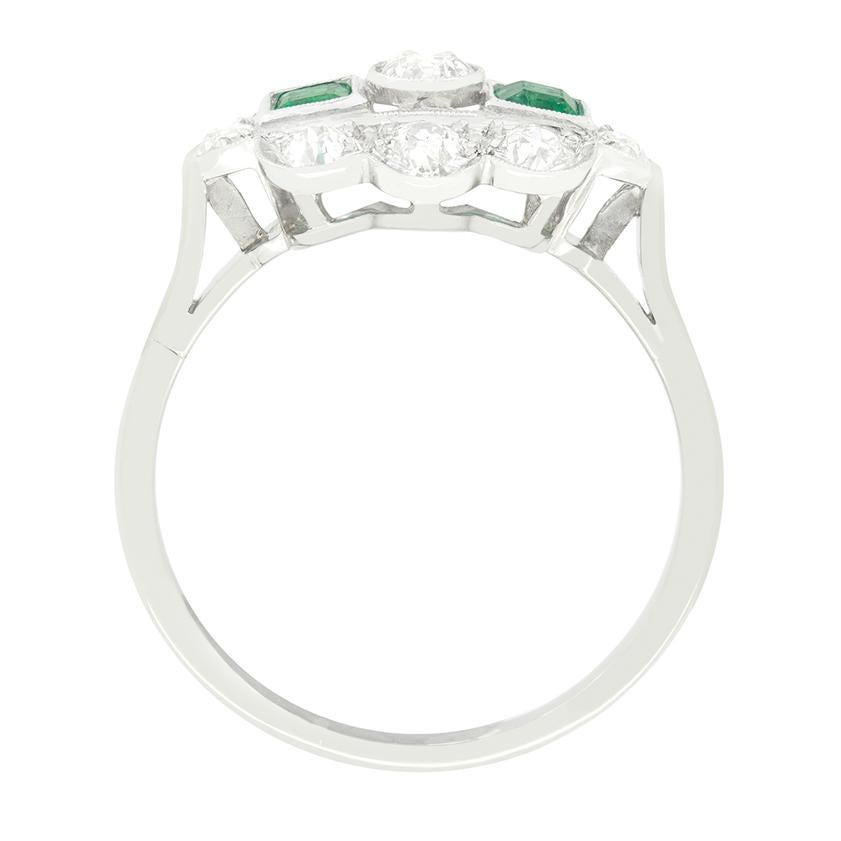 Dating to the Art Deco era, this beautiful cluster ring centres around a single old cut diamond, flanked by emeralds. The central diamond weighs 0.25 carat, with each of the flanking baguette cut emeralds weighing 0.30 carat a piece. These rub over