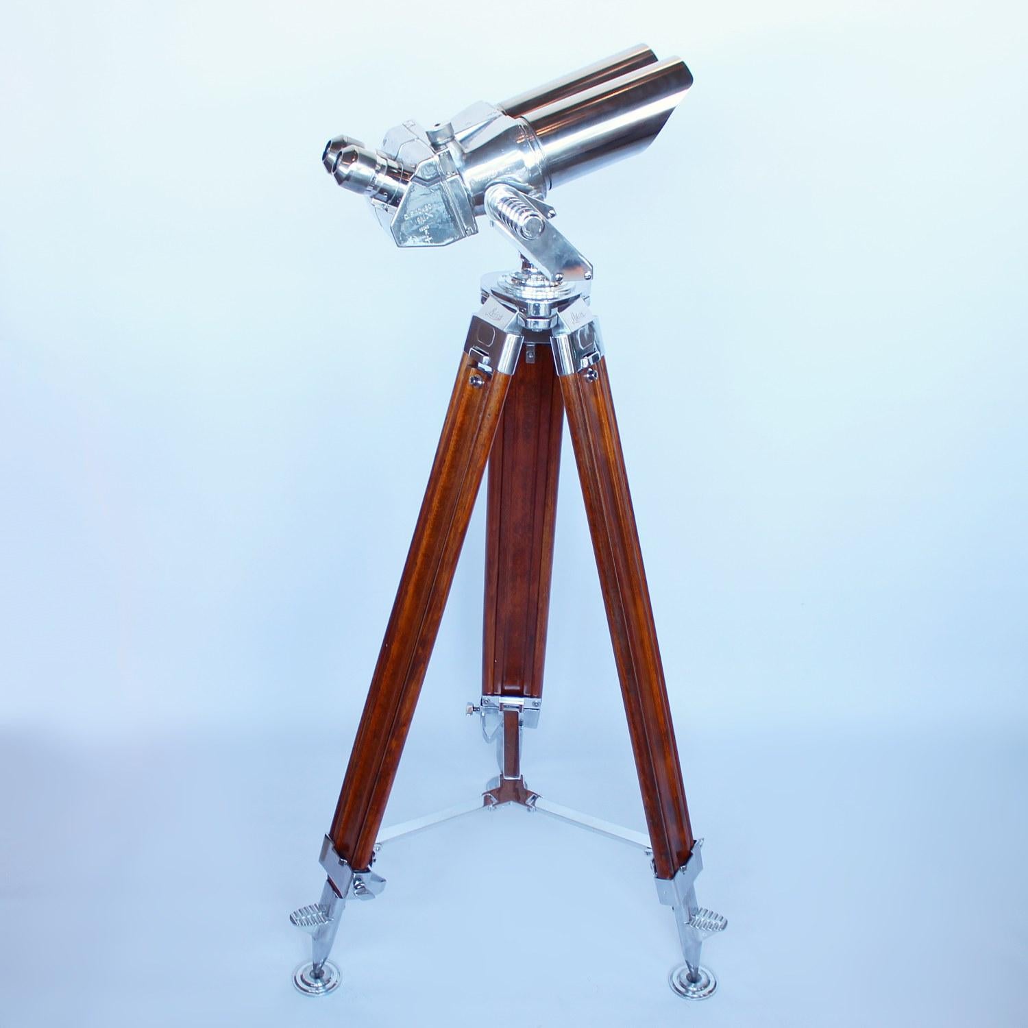 A pair of 10 x 80 binoculars with eyeglasses set at 45 degrees, attributed to Zeiss. Set on period, extending oak and metal Leica stand with chromed, conical feet. 10 times magnification with 80mm objective lens.
Paint stripped and metal polished.