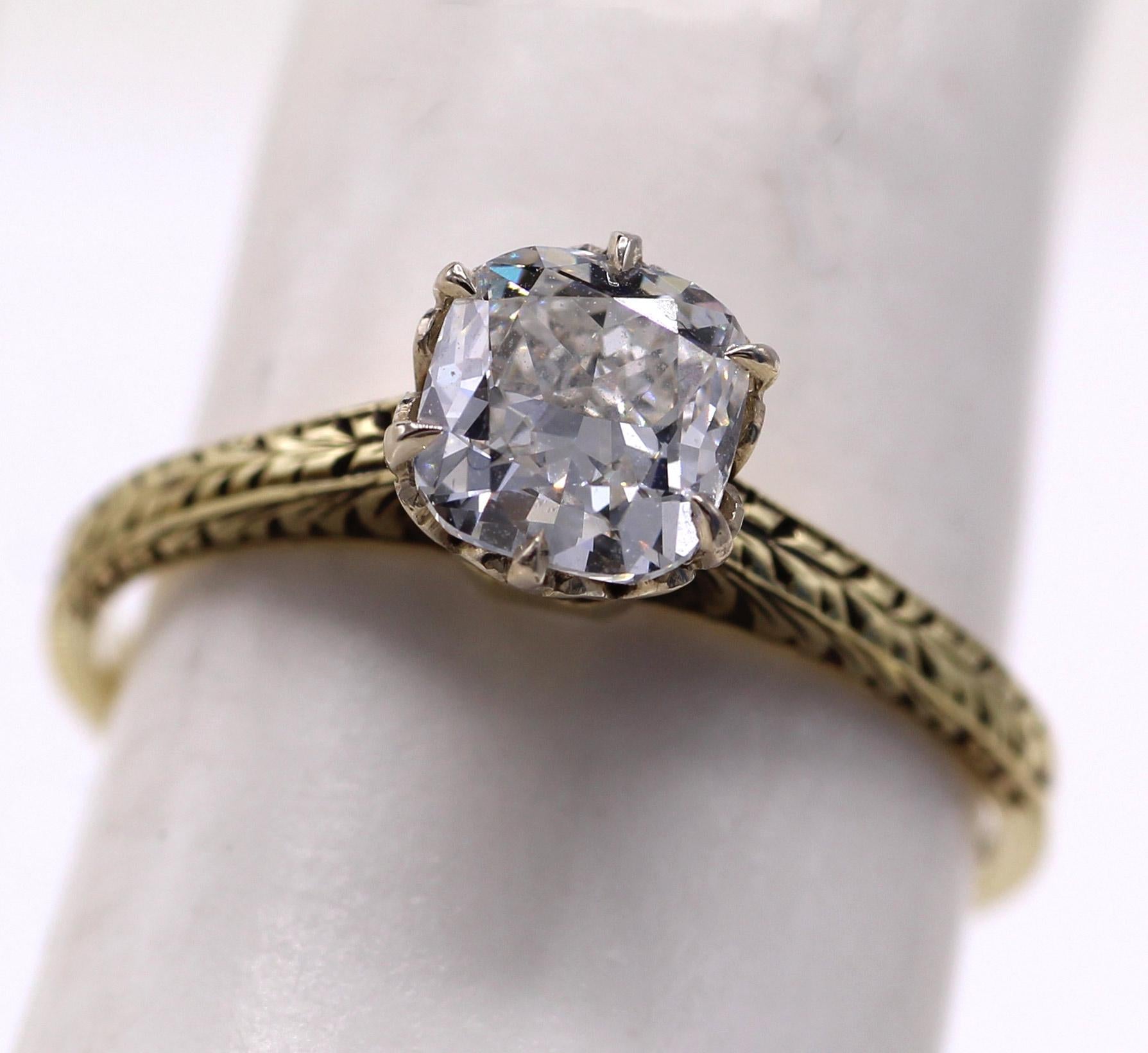This charming engagement ring from ca 1936 features a bright white and lively cushion diamond weighing 1.1o carats, accompanied by a report from the GIA grading it G VS1. Secured by 6 eagle-claw prongs on a white ornate gallery and a hand engraved