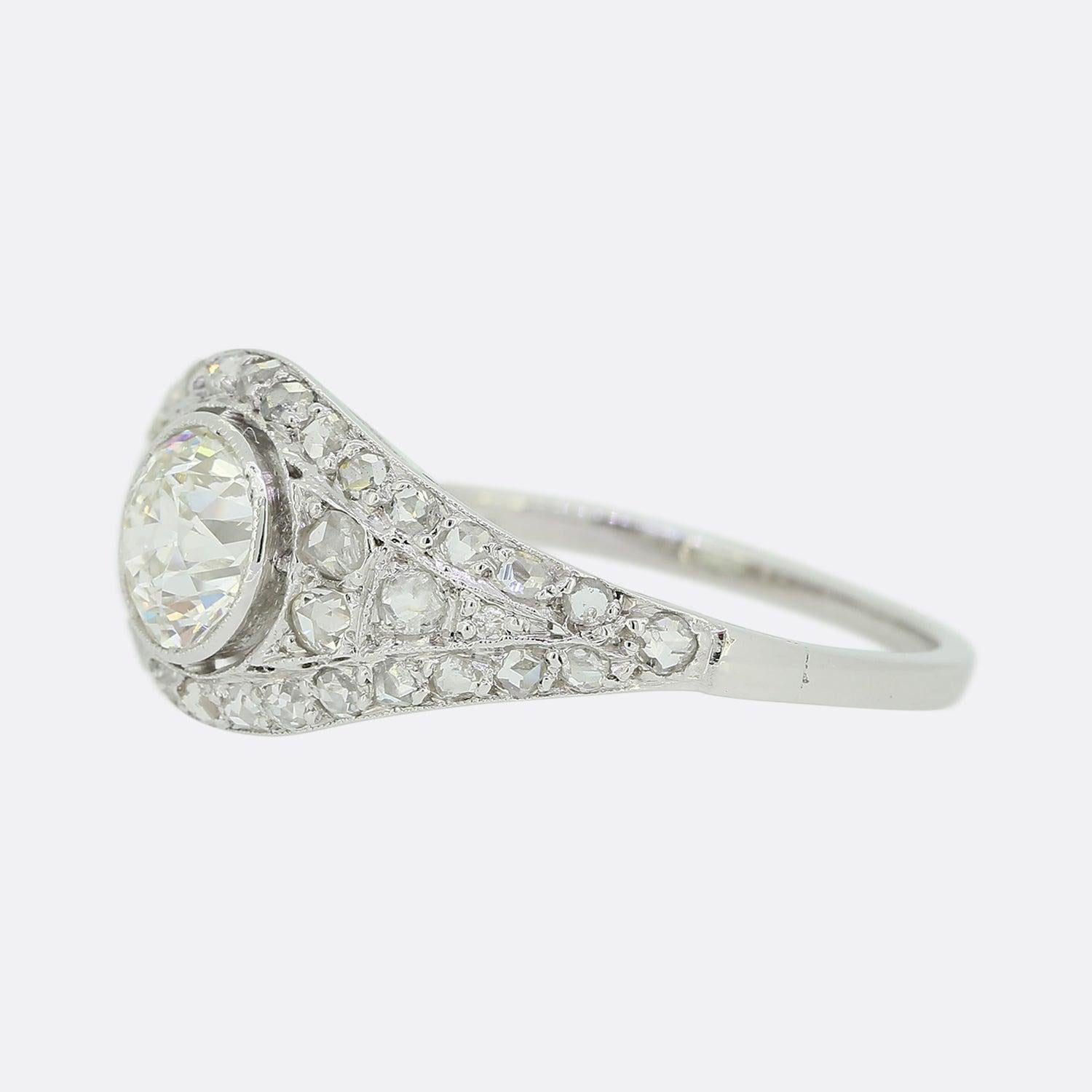 Hier haben wir einen Art-Déco-Ring aus Platin mit Diamanten besetzt. In der Mitte des Rings befindet sich ein beeindruckender, leicht ansteigender Diamant im alten Schliff mit Maserung. Doch erst durch die feine Maserung, die sich durch das gesamte