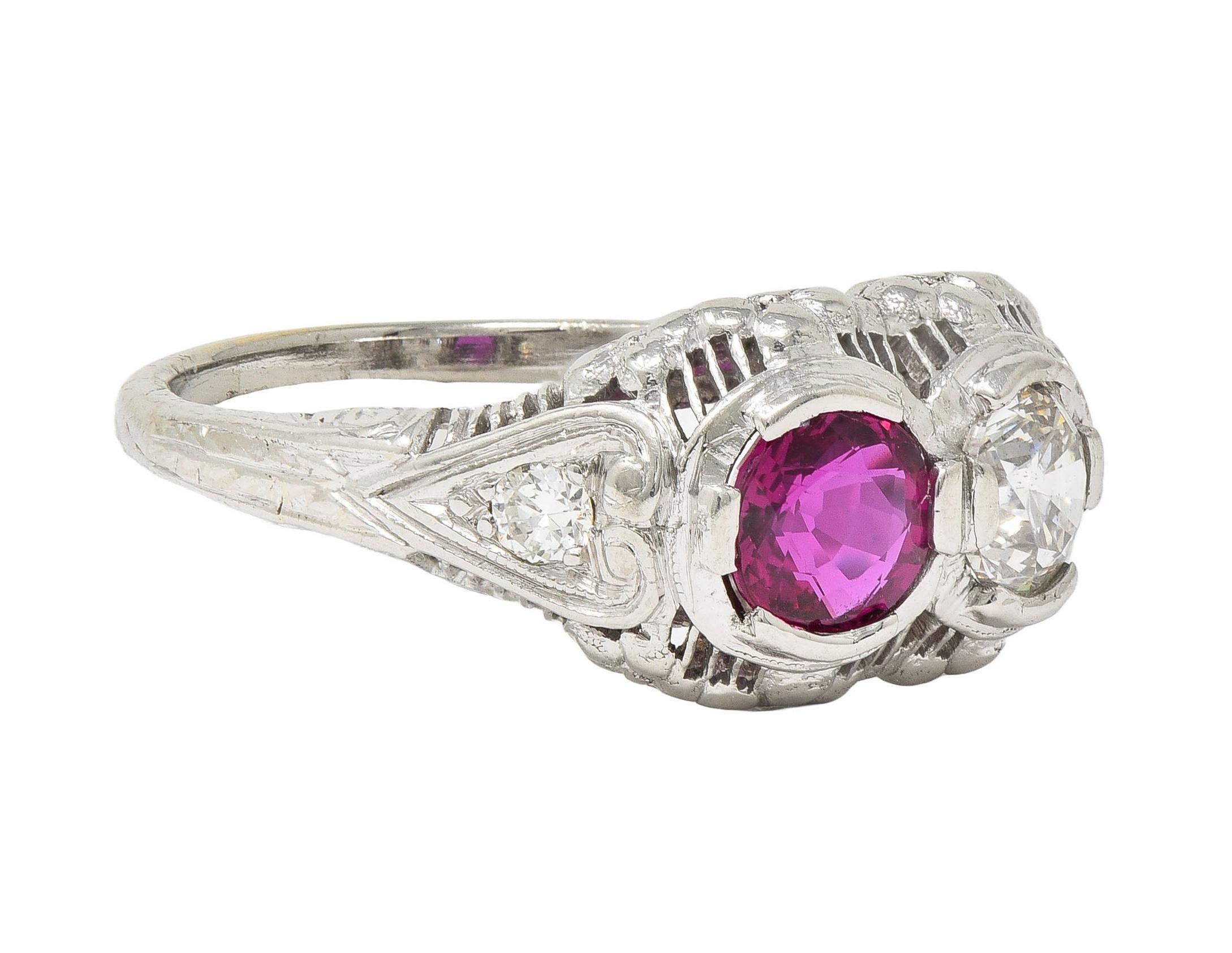 Centering a round cut ruby and transitional cut diamond prong set east to west 
Toi-et-moi style, which translates from French to 'You and Me' 
Ruby weighs approximately 0.49 carat - transparent medium purplish red
Natural Thai in origin and