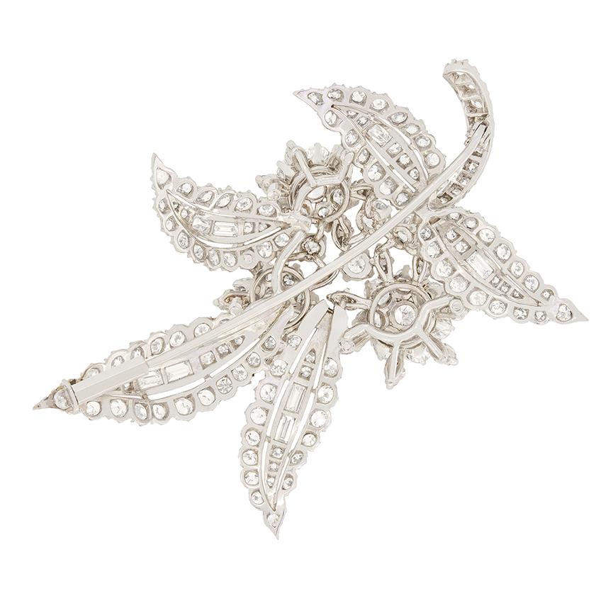 Diese atemberaubende Art-Déco-Brosche verströmt Eleganz mit insgesamt 11 Karat Diamanten im Übergangsschliff und Baguetteschliff, die kunstvoll zu einem zarten Blumenmuster angeordnet sind. Die Diamanten im Baguetteschliff schmücken die Mitte jedes