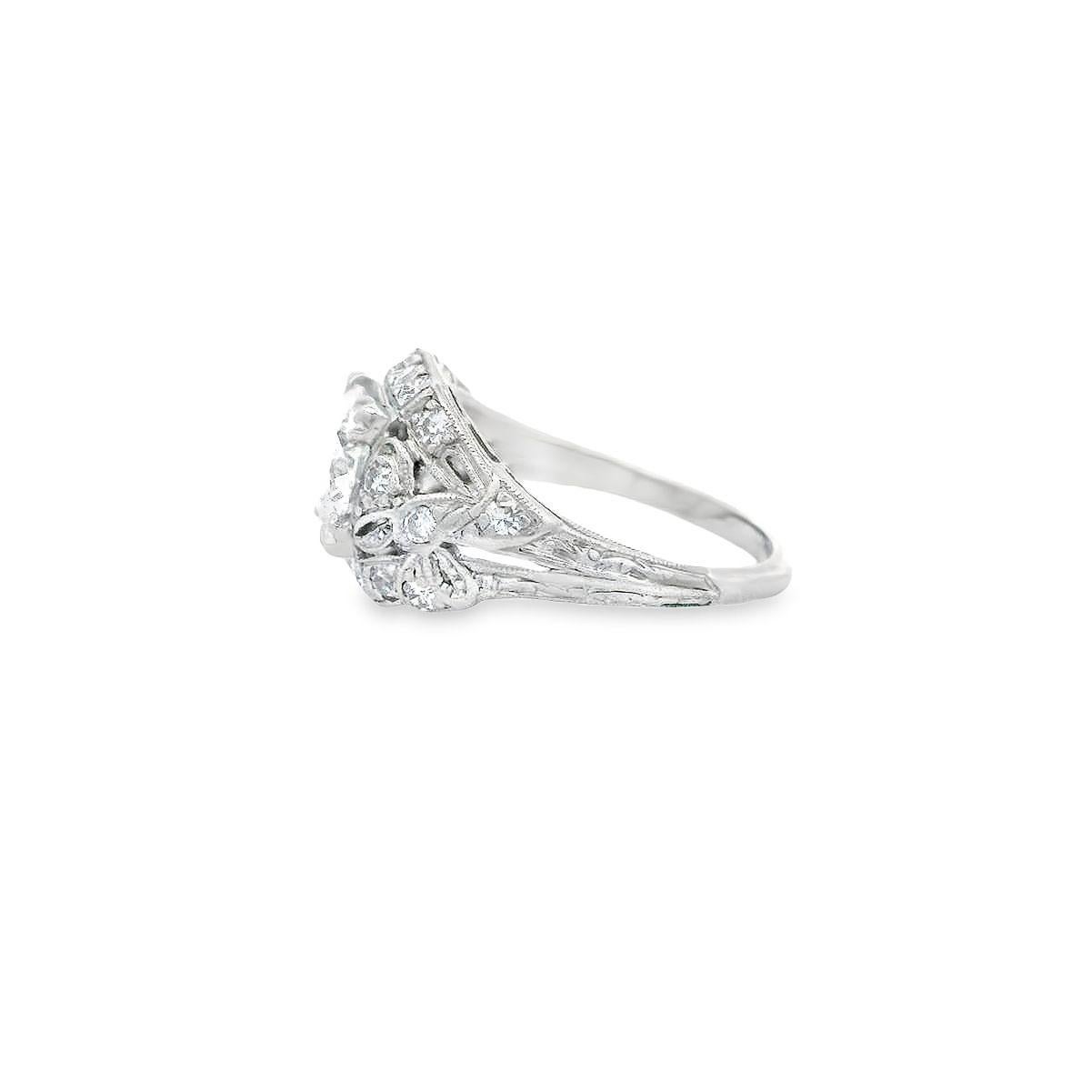 A captivating vintage diamond ring offered  by Alex & Co. This refined low profile platinum ring features a triple prong set center transitional cut round diamond weighing 1.10ct with a color grade of D and SI2 clarity. On the shoulders are