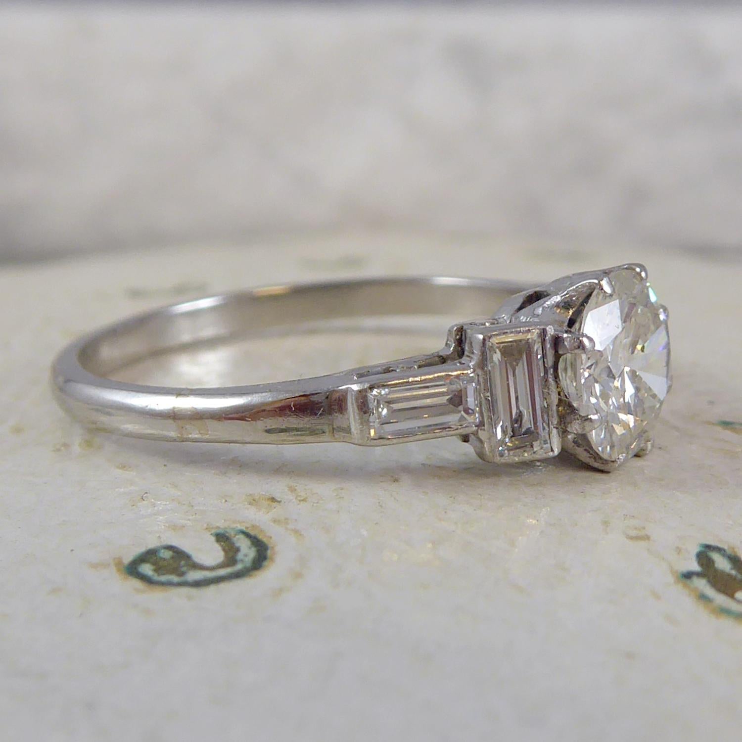A very striking art deco design diamond ring set to the centre with a round brilliant cut diamond 0.76ct and measuring approx. 5.98mm-6.03mm diameter x 3.46mm deep.  Calculated weight 0.76ct with assessed colour I/J and assessed clarity SI2.  White