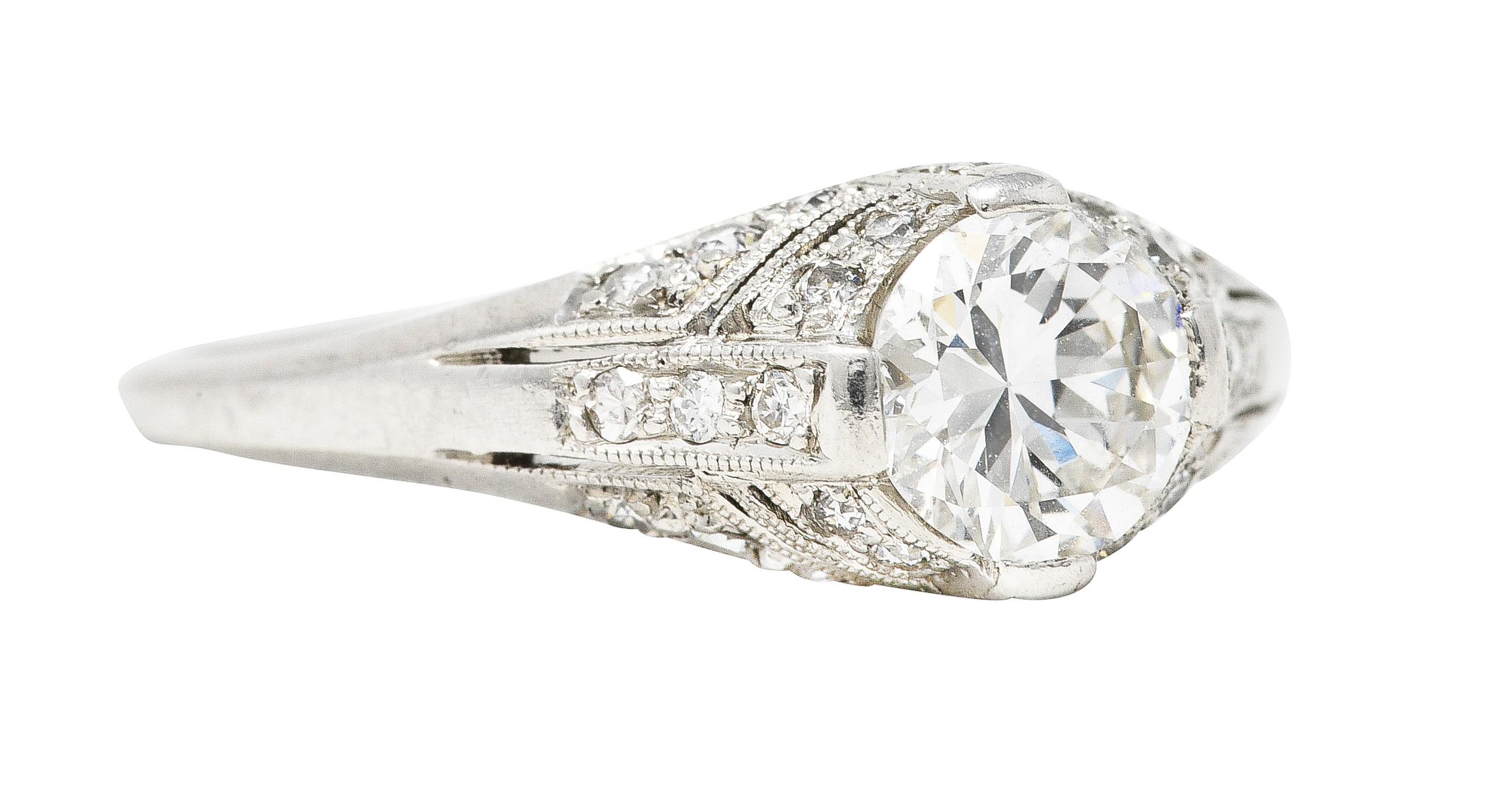 Featuring a transitional cut diamond weighing approximately 0.64 carat - G color with VS2 clarity. Set low in a bombé style mounting via wide prongs with milgrain edges. Bead set throughout by single and old European cut diamond accents. Weighing