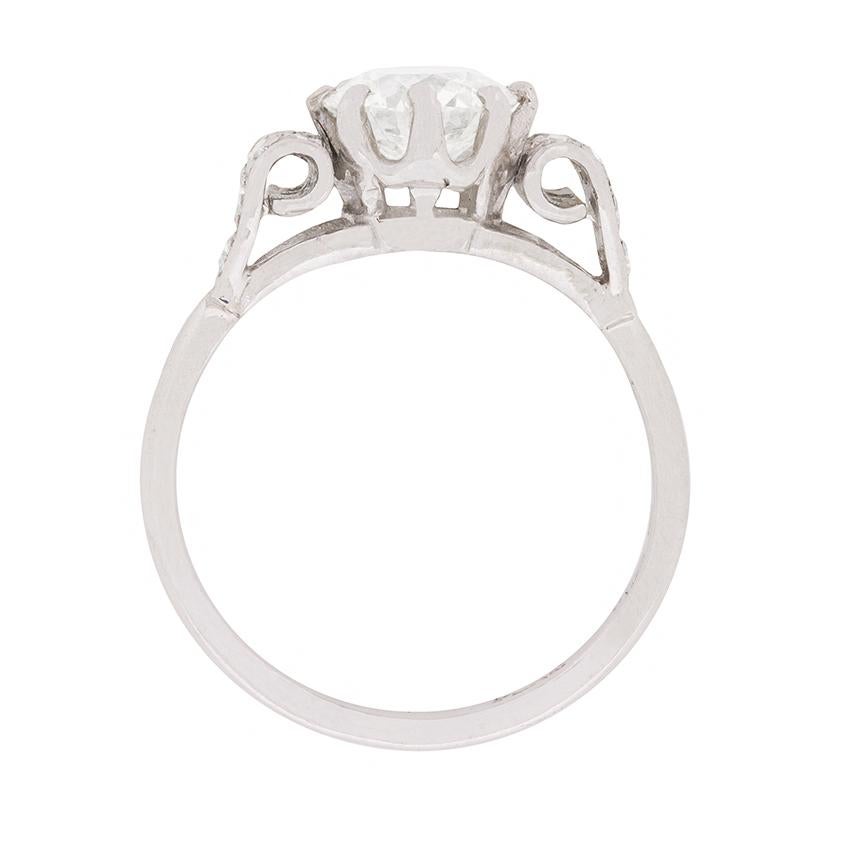 This beautiful and unique engagement ring dates back to the 1930s. It has a central diamond weighing 1.15 carat. The sparkling round brilliant has been expertly claw set with scroll shoulders either side. The detailing is impeccable and the