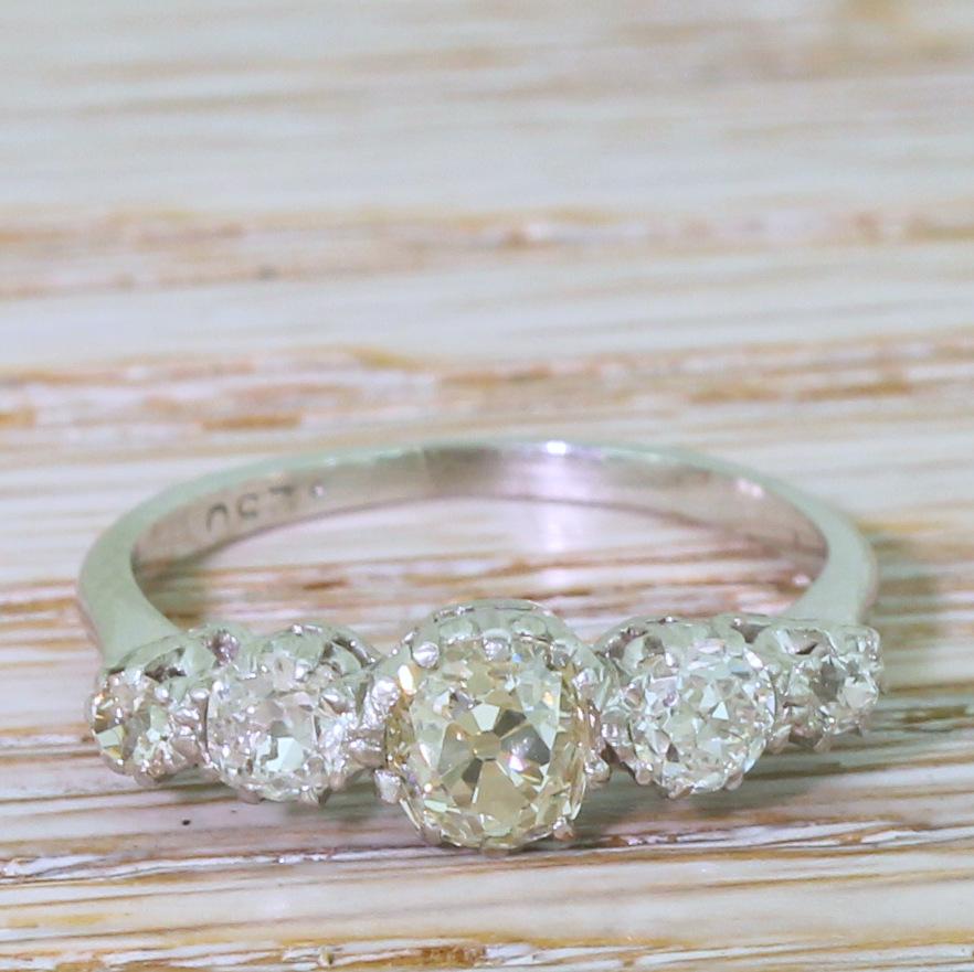 A delightfully unique vintage five stone ring. The centre stone – weighing approximately 0.70 carat – is bright, internally clean and displays a clear, light yellow tone – with the whiteness of the four diamonds either side emphasising the colour of