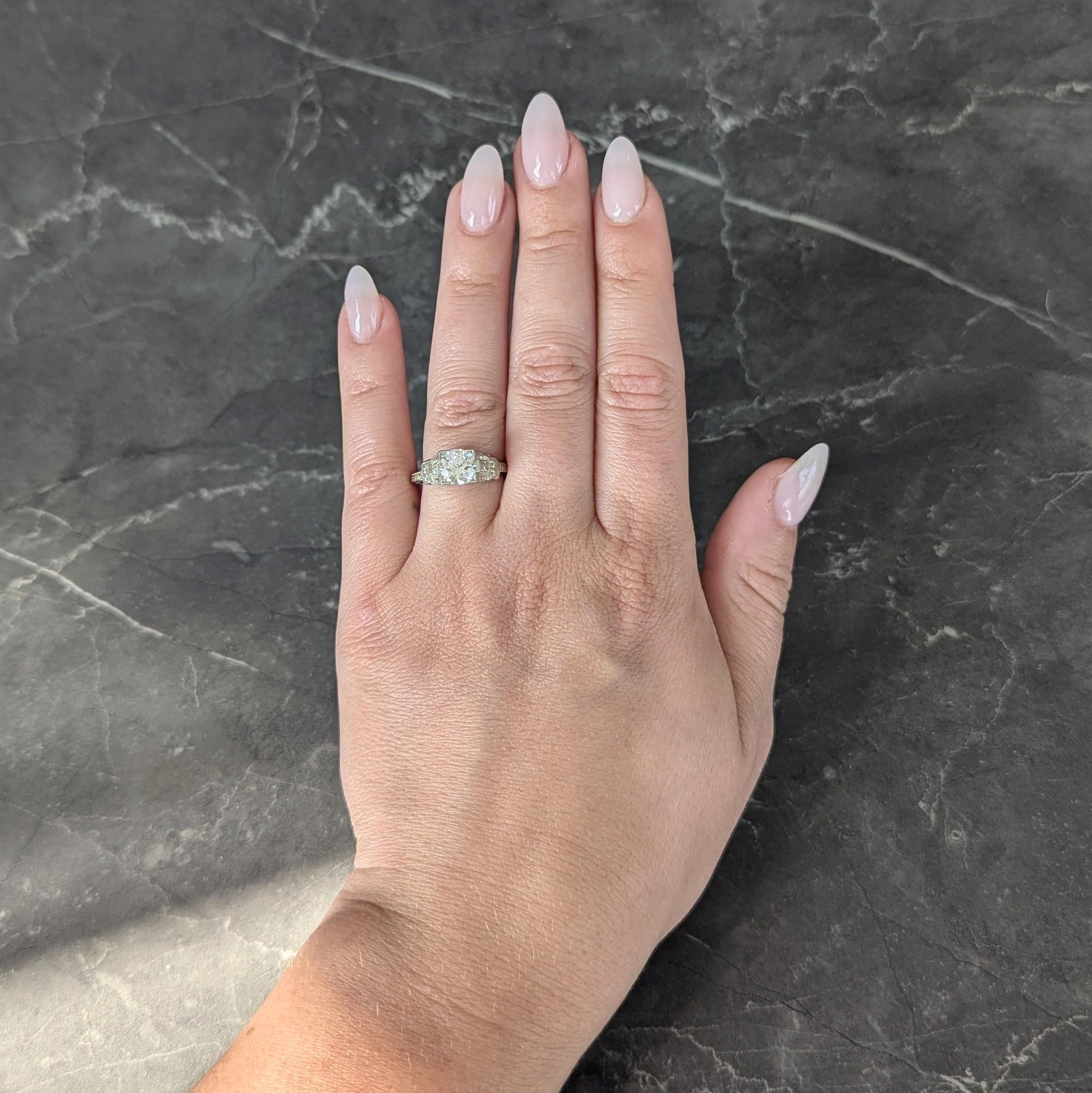 Centering a transitional cut diamond weighing approximately 1.16 carat - G color with VS2 clarity
Bead set in a square form head and flanked by pierced buckle motif shoulders
With criss-cross motif profile - all engraved with orange blossom