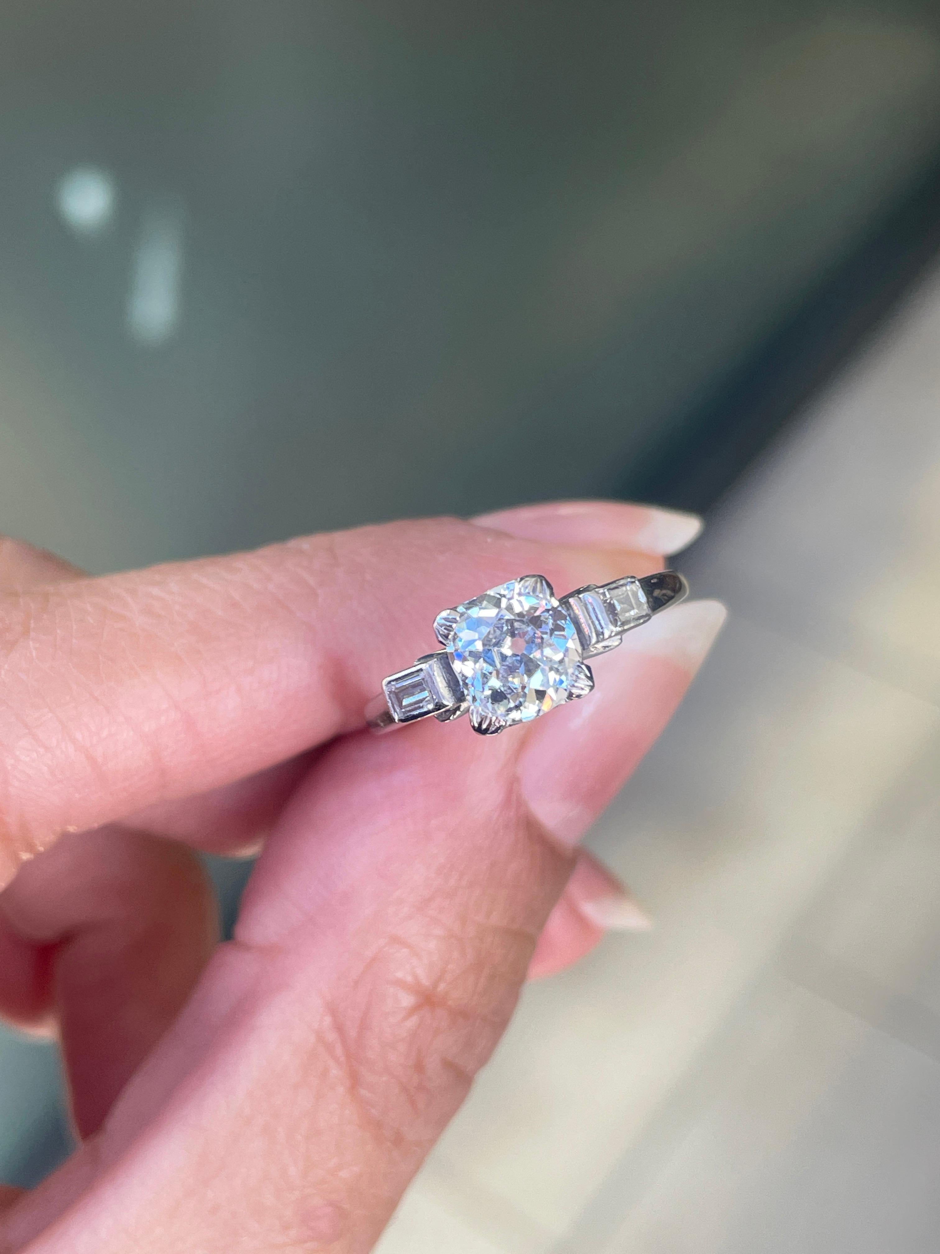 The unique beauty of this magnificent engagement ring cannot be matched!

This wonderful antique three-stone engagement ring is beautifully centred with an old mine cut diamond weighing 1.17ct, mounted in an open back setting and secured within four