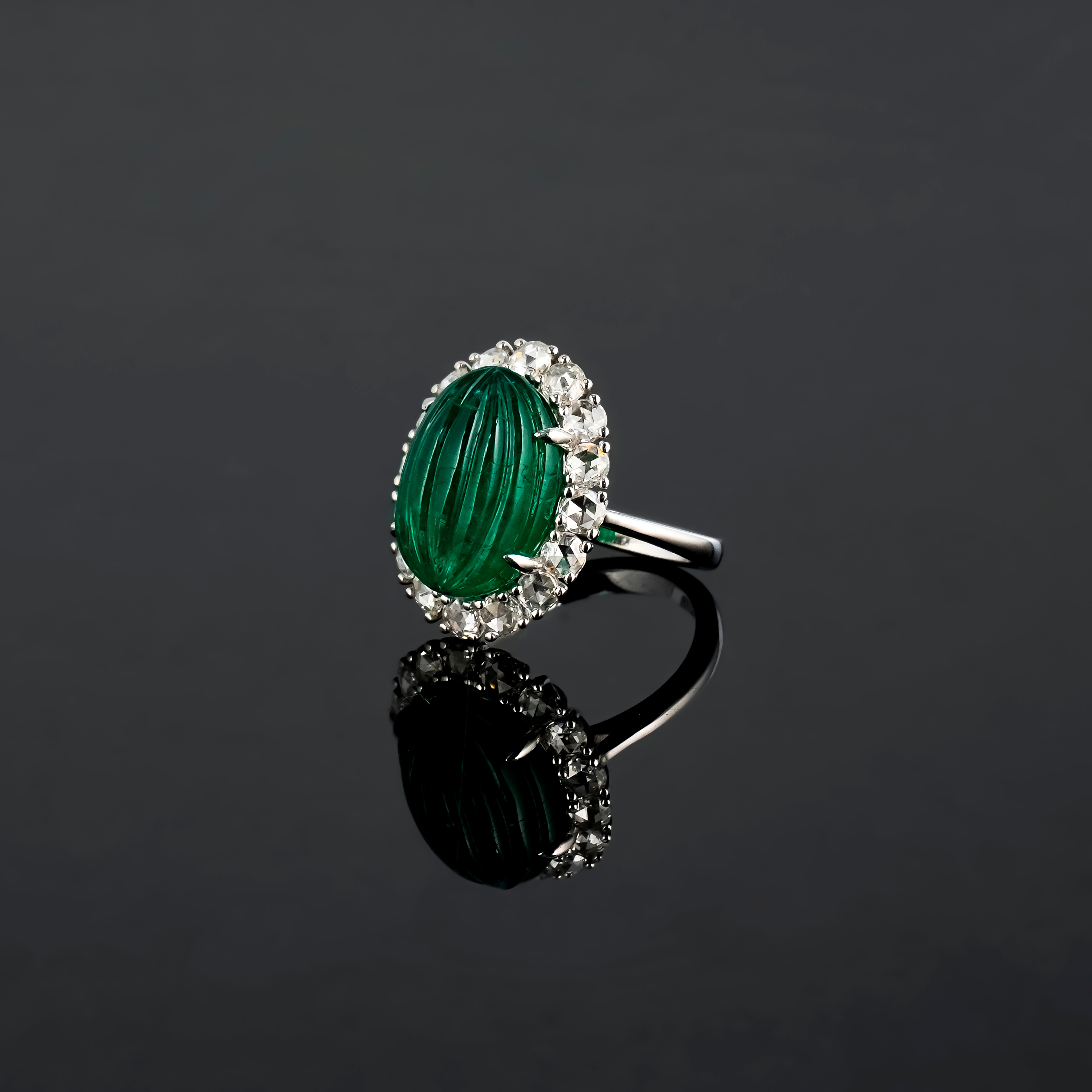 Ein wunderschöner, im Art-Deco-Stil gehaltener 11,82 Karat schwerer ovaler Smaragd mit geschnitztem Mittelstein aus Sambia, der mit 1,26 Karat Diamanten im Rosen- und Brillantschliff verziert ist. Der Smaragd ist transparent, mit einer schönen