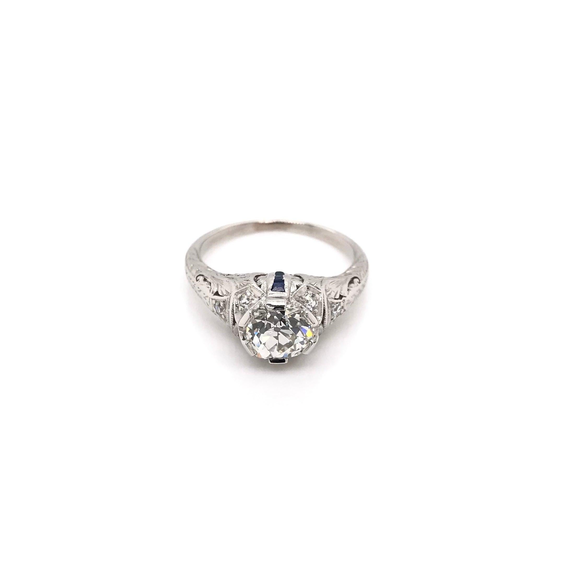 This antique piece was handcrafted sometime during the Art Deco design period ( 1920-1940 ). The setting is 18k white gold and features quite a few enchanting Art Deco design elements. The center diamond is an old mine cut measuring approximately
