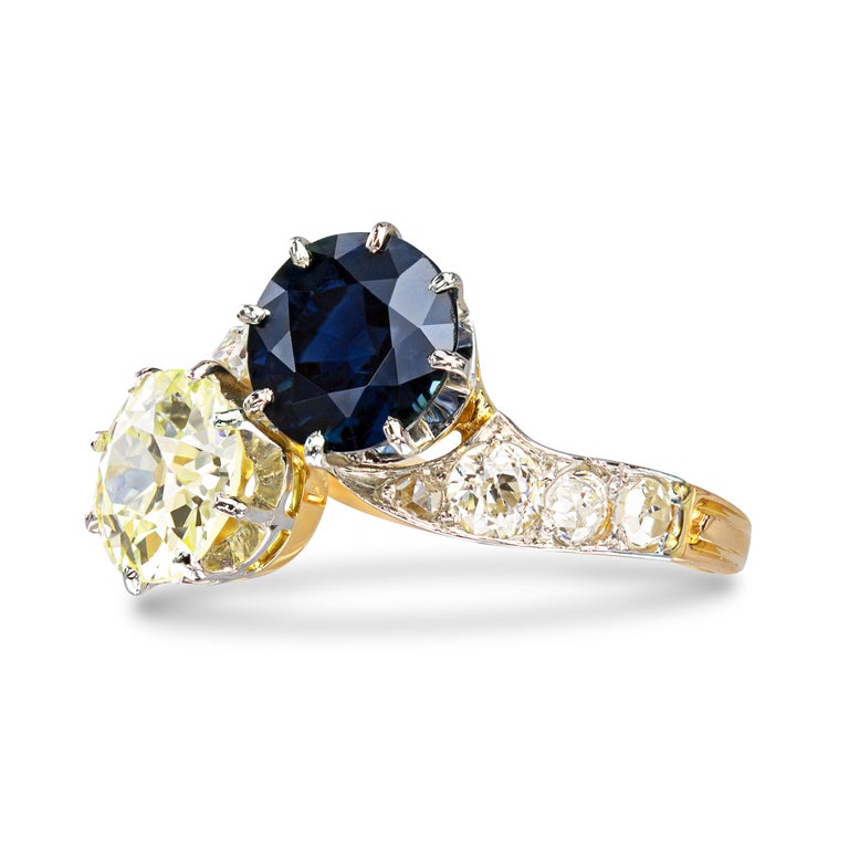 A deco delight in every sense of the word. This swirling Toi et Moi ring, likely dated back to the early deco era, features a classically proportioned Old European cut with so much personality. A deep blue antique sapphire is the perfect complement
