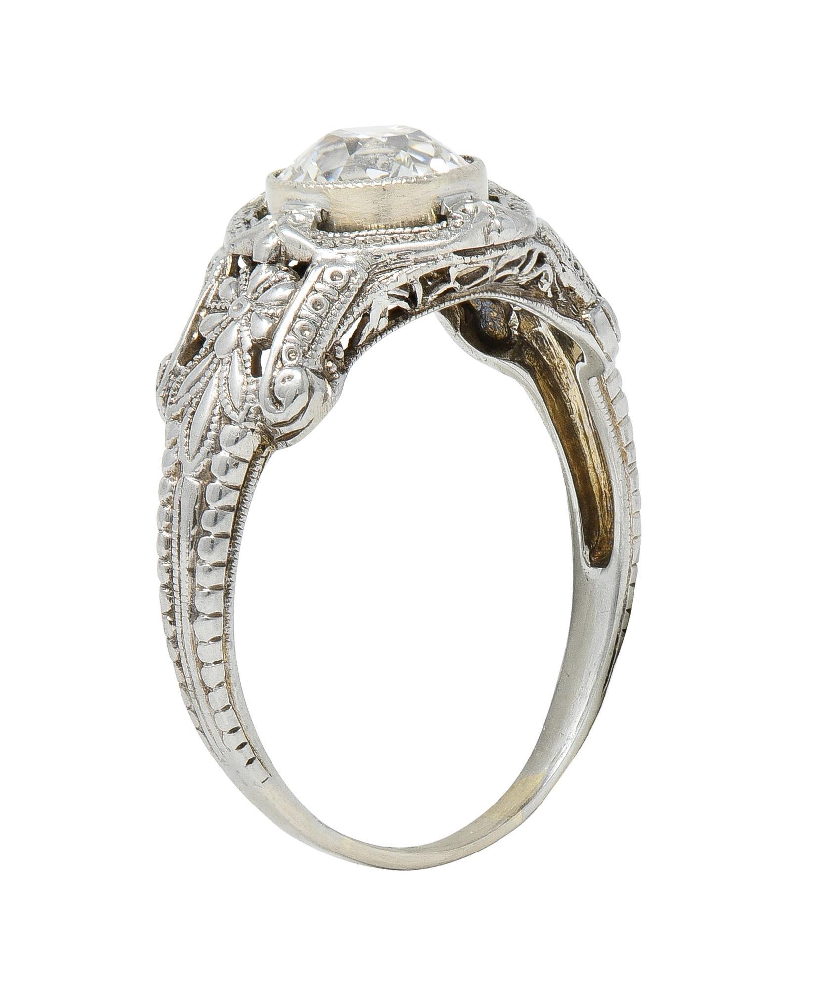 Centering a bezel set old European cut diamond weighing 1.19 carat total - J color with SI1 clarity
Accented by milgrain surround with decorative engraving
Flanked by floral motif shoulders
With pierced scrolling profile
Stamped 18k for 18 karat