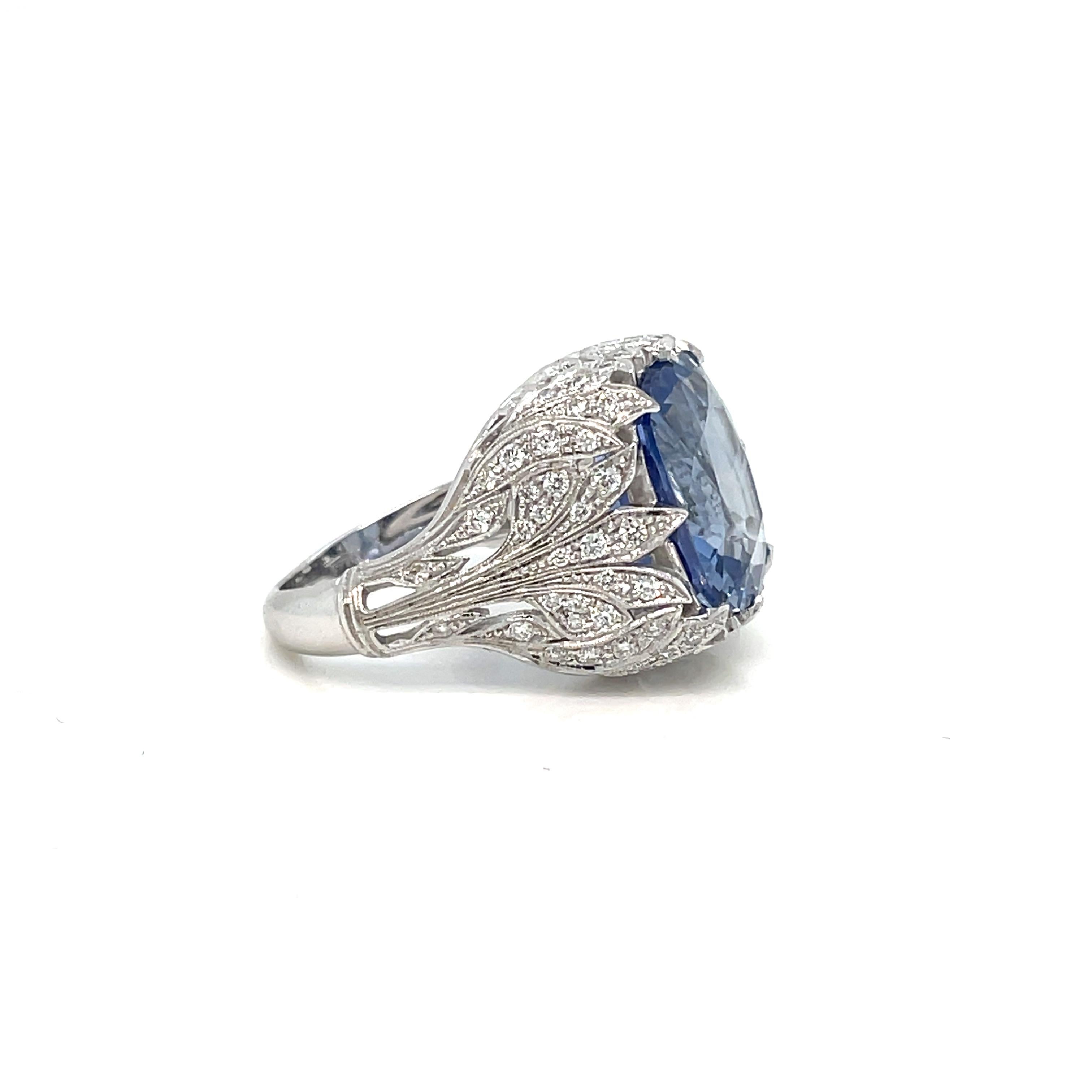An exquisite genuine Art Deco style ring handcrafted in 18 kt gold by master jewelers, featuring an amazing rare vivid 12,24 carat  Natural Ceylon Sapphire cushion-shape, surrounded by 0,70 carats of round brilliant cut diamonds - VVS clarity, G
