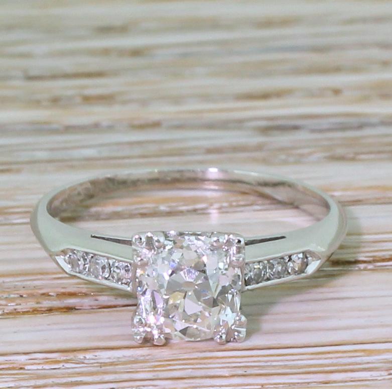 A nigh on perfect diamond engagement ring. The glowing and vibrant old cut diamond is white, bright and internally clean. Secured by four triple-claws to neatly shaped and etched gallery. Each shoulder holds three eight-cut diamonds leading to a