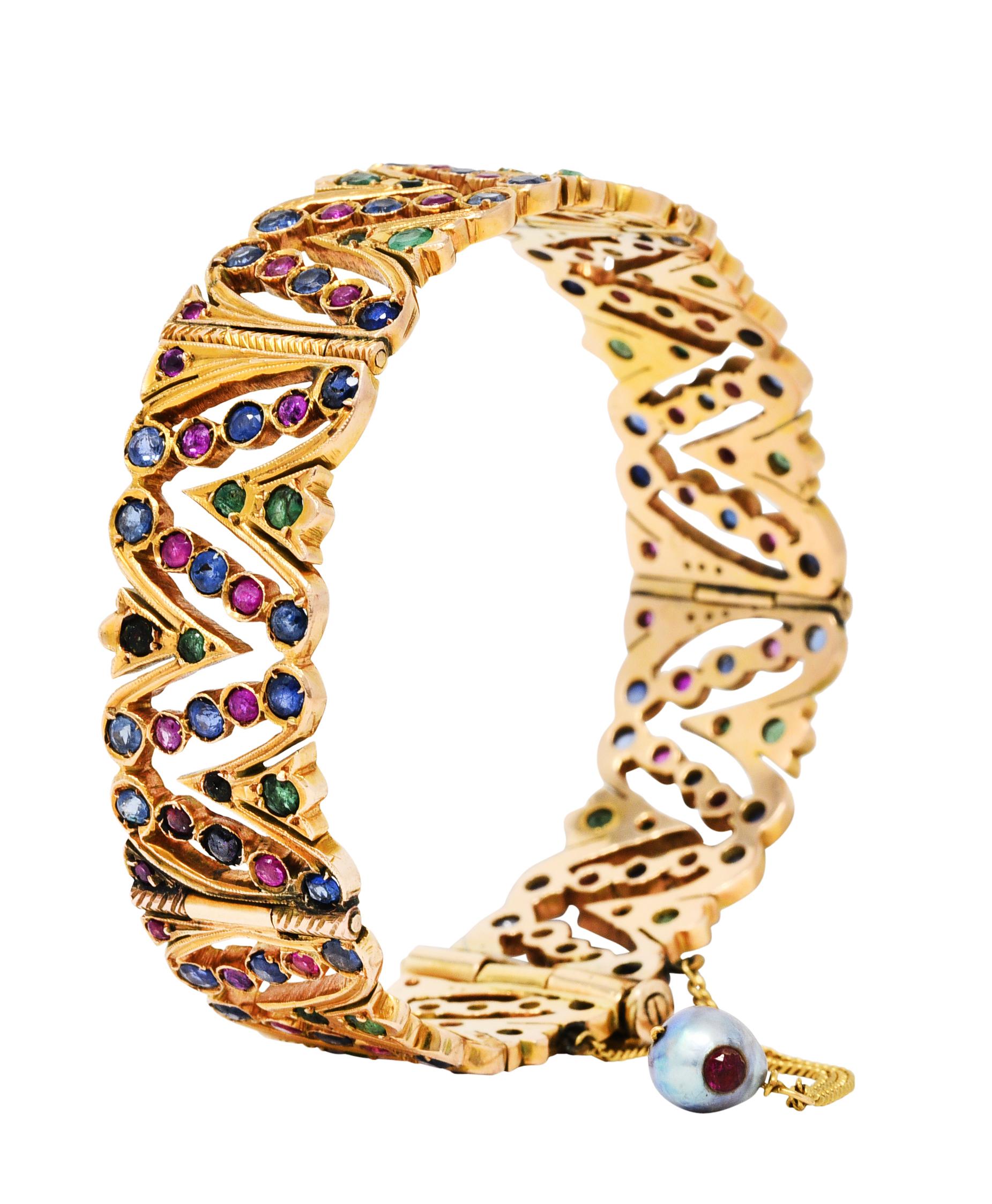 Wide bracelet comprised of hinged panel links

Pierced with stylized foliate accented by milgrain and ribbed texture

Accented throughout by round cut emeralds, rubies, and sapphires

Rubies are translucent with natural inclusions while weighing