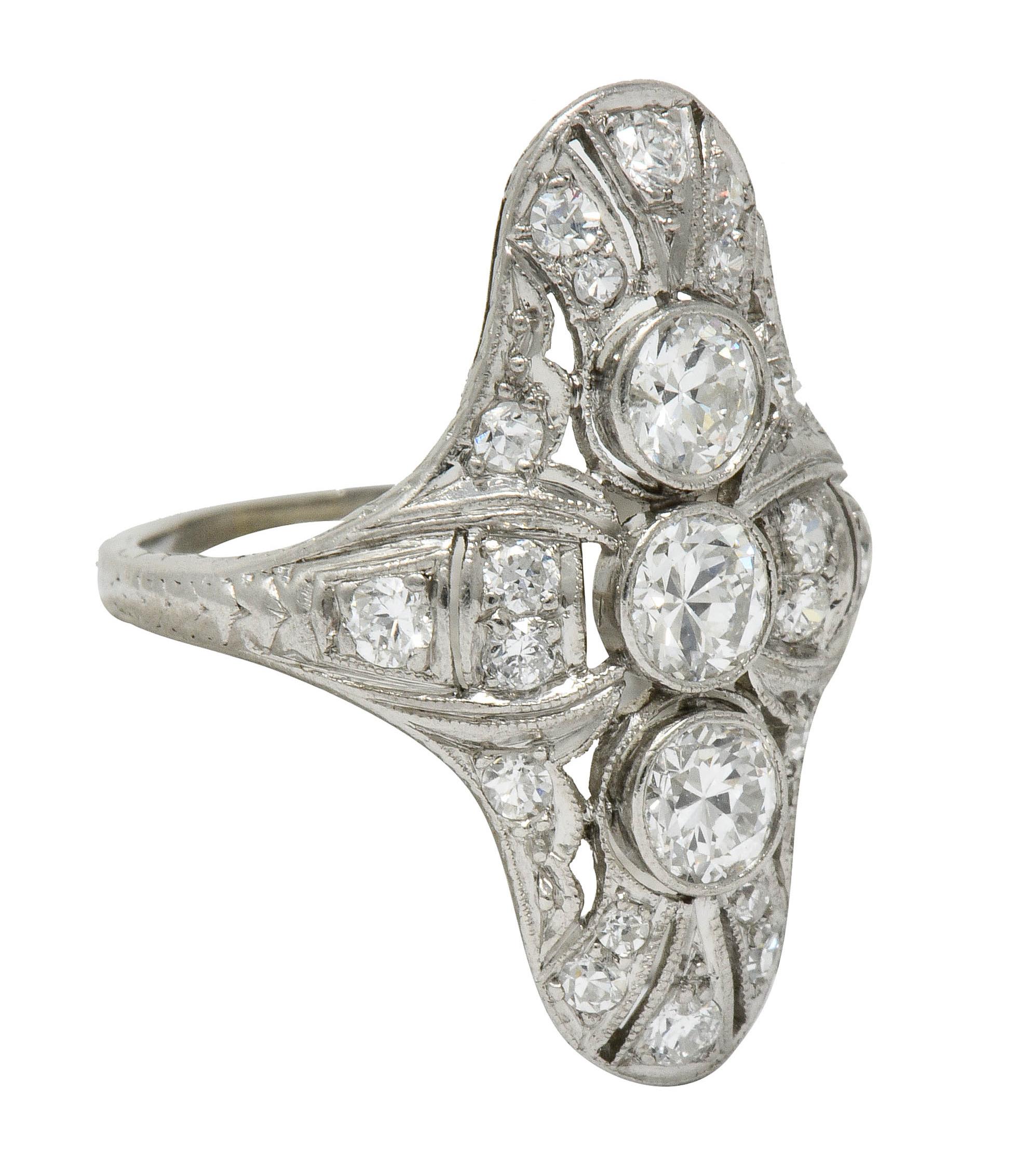 Dinner style ring centering three transitional cut diamonds weighing in total approximately 0.75 carat; H/I color and VS clarity

Bezel set North to South in a pierced milgrain mounting with engraved foliate shoulders

Accented throughout by round